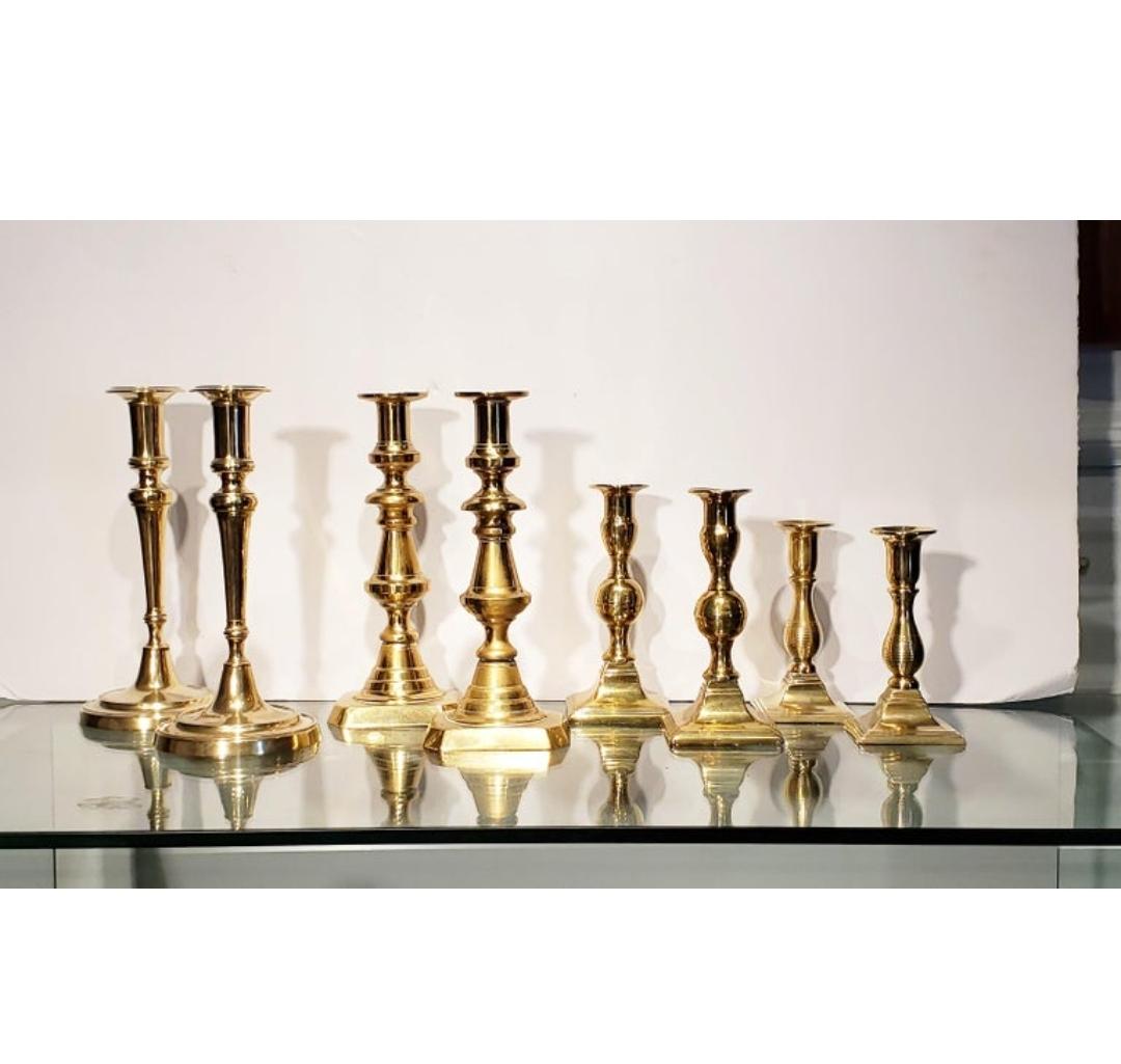 A collection of Georgian brass antique taper or candlesticks including 8 sticks making 4 pairs. The collector used them to lean a place card on. A dinner party table set with 8 candlesticks with flickering tapers must be be an enchanting sight. What