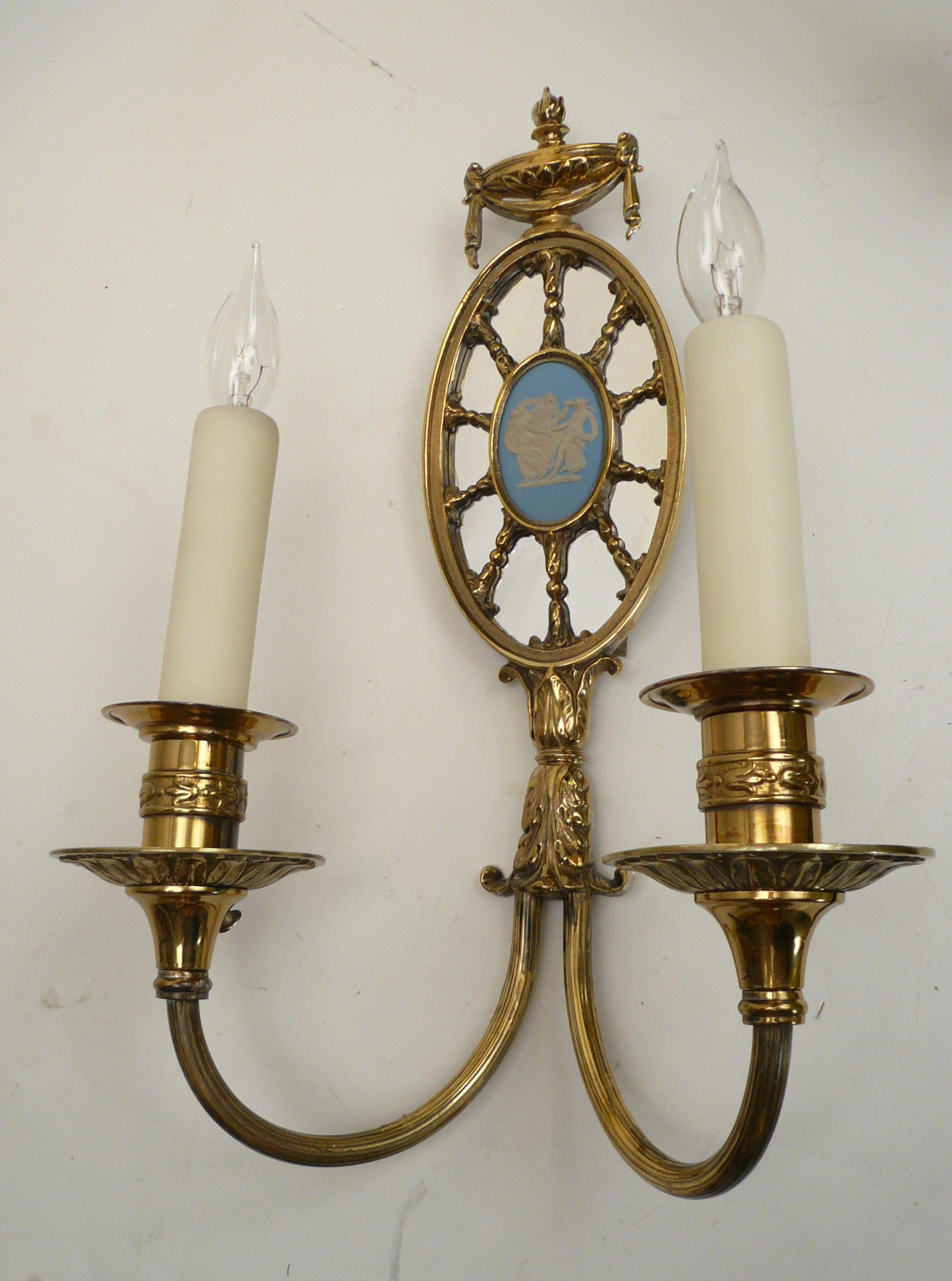 These handsome Robert Adam style sconces feature Classical motifs including urns, swags, and acanthus leaves. They are mounted with signed Wedgwood jasperware oval plaques.