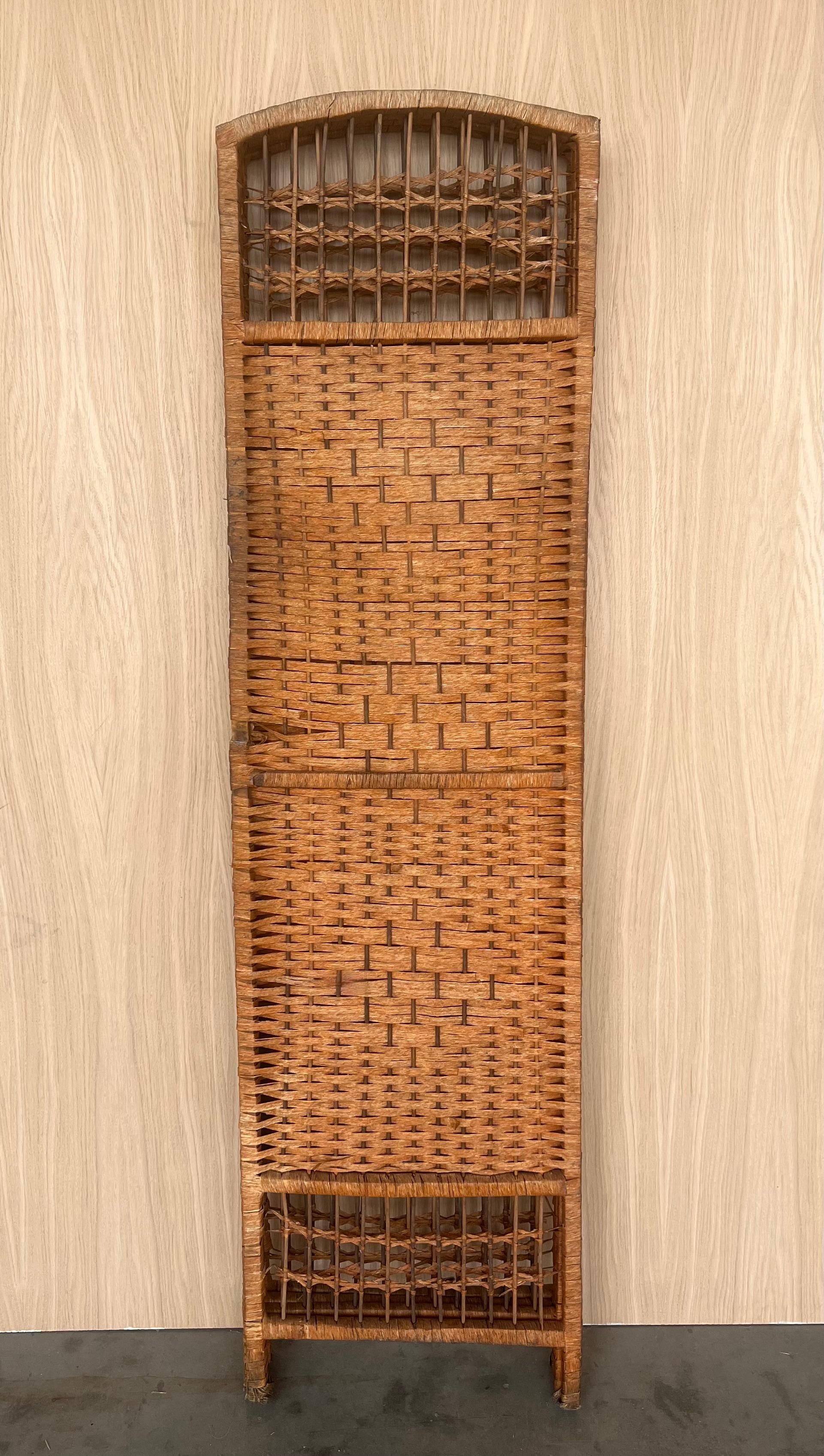 This Mid-Century-Modern eye-catching rattan or wicker and bamboo four-panel room divider with filigree decoration was crafted in France in the 1960s. This rattan screen combines mid-century and chinoiserie accents with a swirling design. 
The design