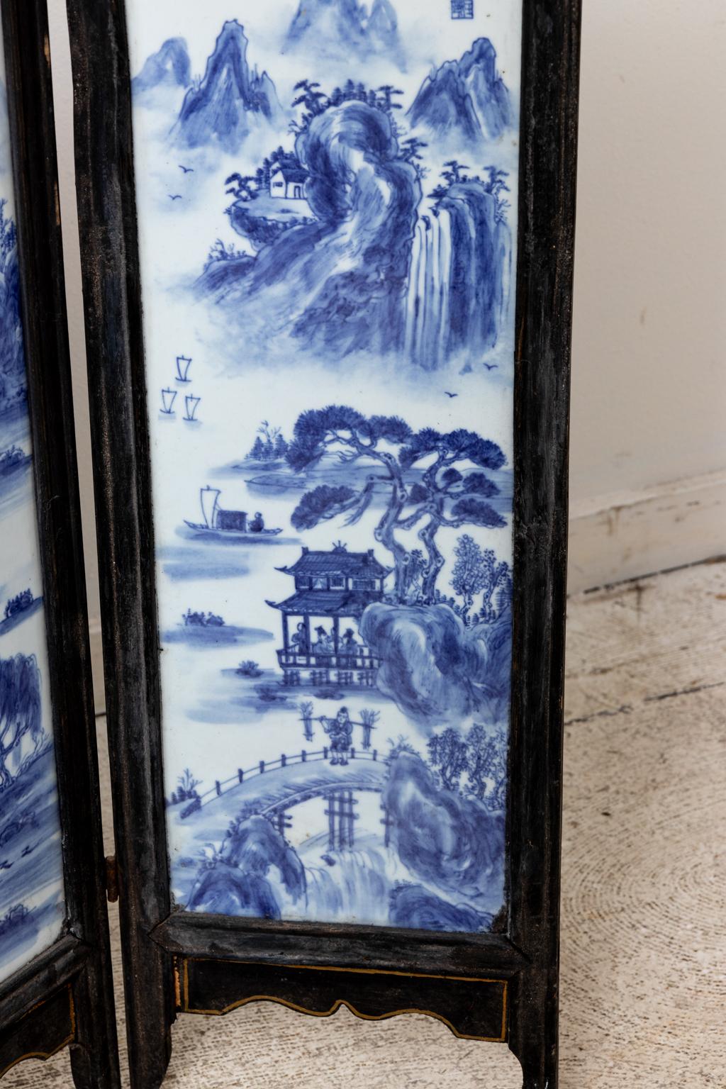 Circa 19th century unusual sized four panel Chinese wood screen inlayed with four blue and white painted porcelain panels of landscape scenes. Smaller floral motifs are also featured above the porcelain panels. Made in China. Please note of wear