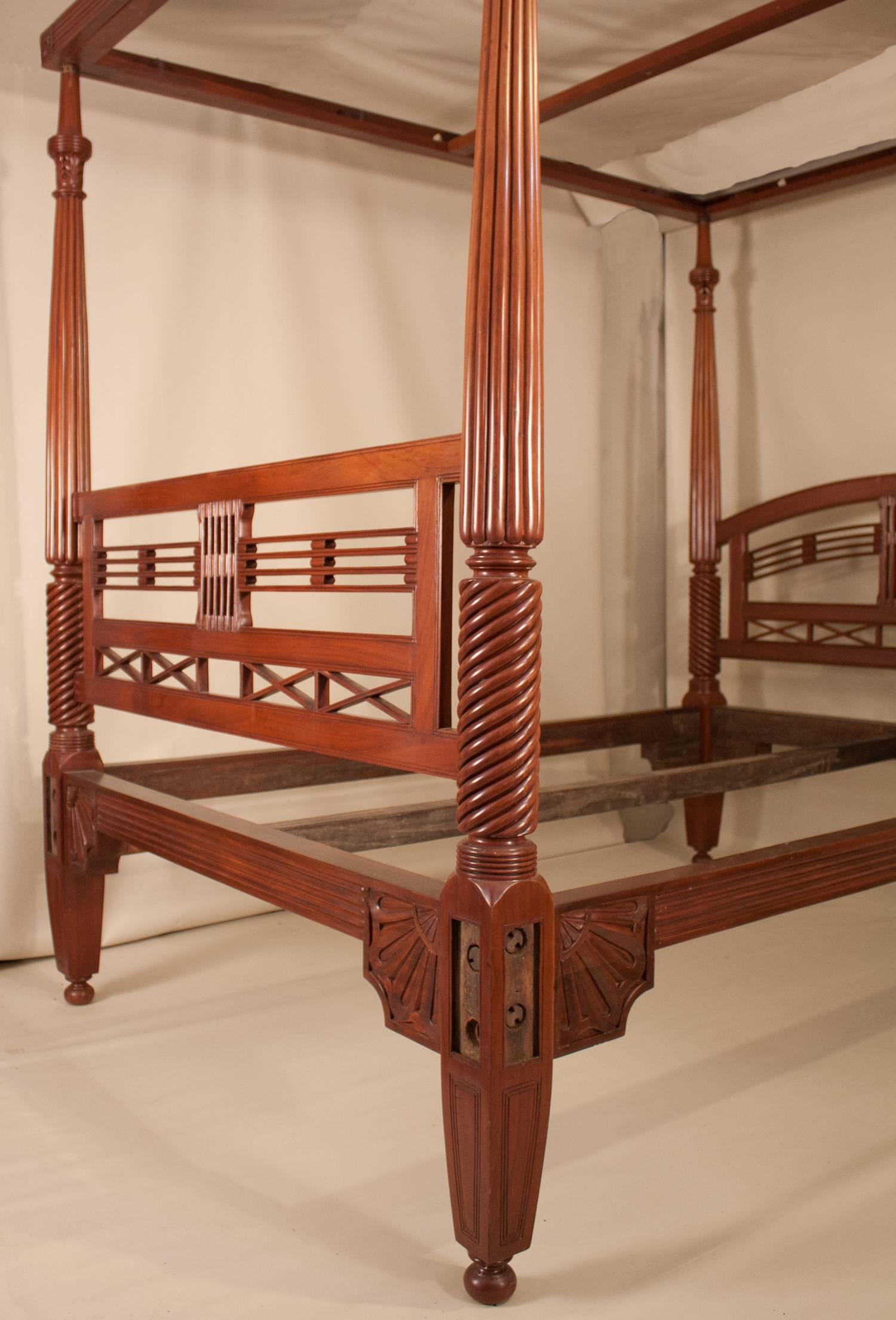 Hand-carved mahogany four post bed from British India, circa 1920. This queen-sized bed, which was restored at some point, has both beautiful wood tone and luster. Its complete tester, or canopy, would have been used as a frame for mosquito netting.
