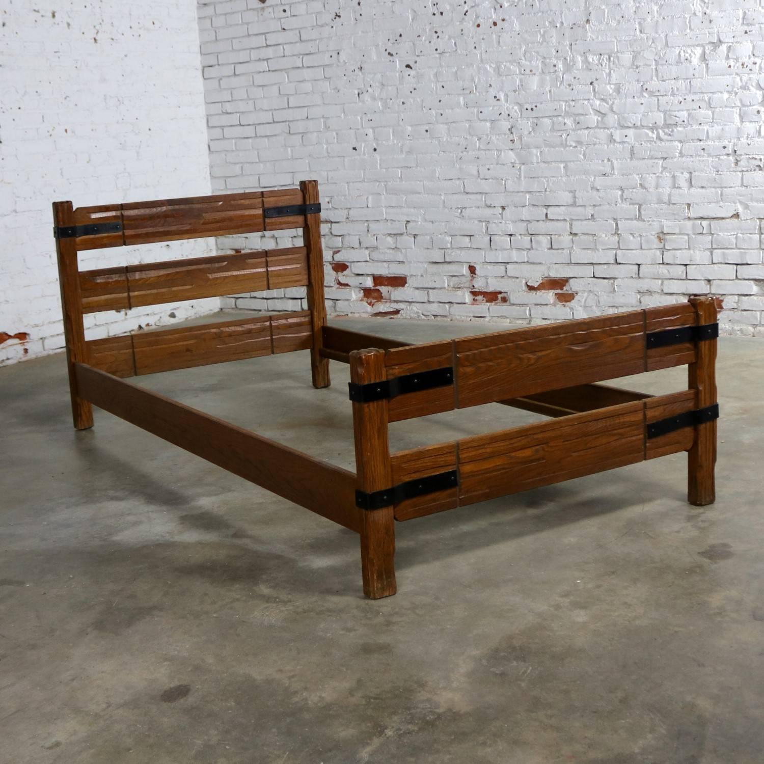 Two cool ranch oak twin beds with a western cowboy design and iron strap detail that are attributed to A. Brandt Company. These beds are in wonderful vintage condition with their original signature finish and includes a headboard, footboard, and