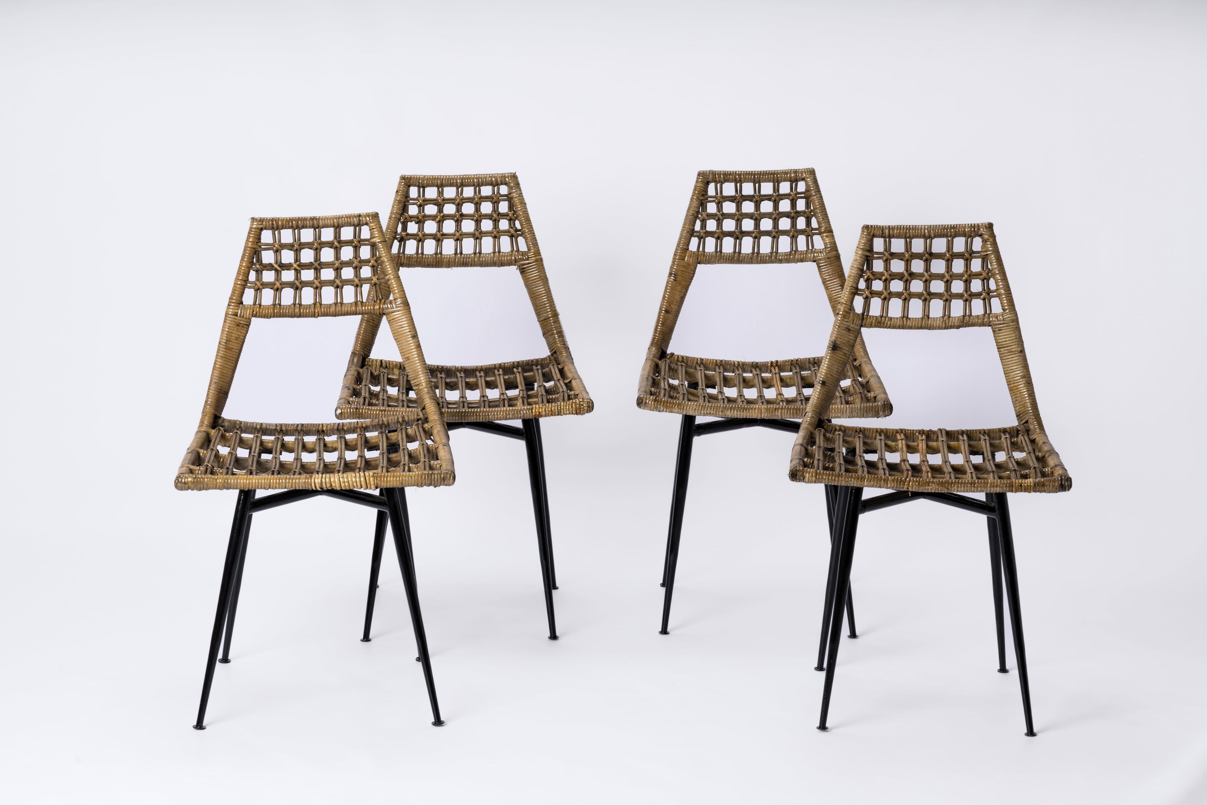 Set of four rattan basket chairs. Black lacquered steel feet. Feet have been repainted. These minimalist chairs have a unique French Reconstruction era look.  Their compact size makes them ideal candidates for side chairs. 
Some repairs have been