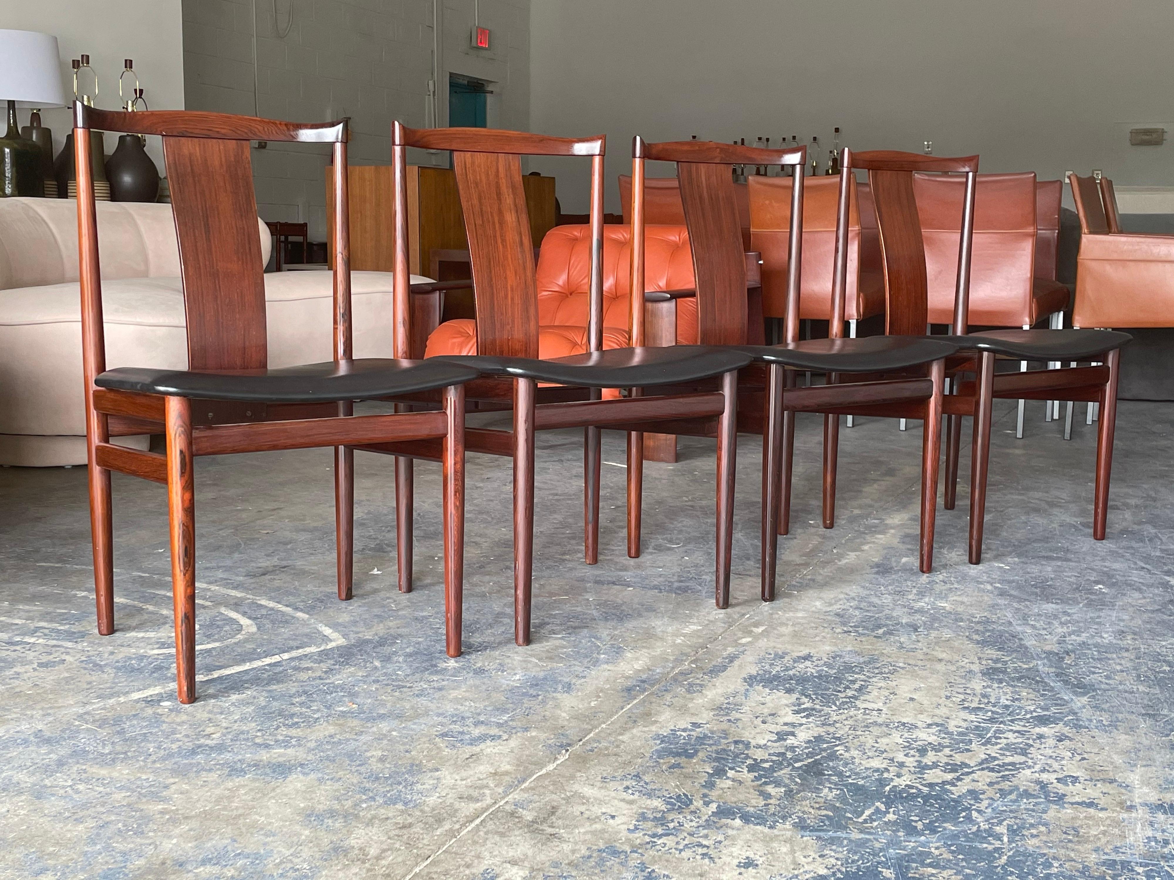 Uncommon set of dining chairs designed by Henning Sorenson. Well constructed, elegant chairs with black vinyl seats. Original condition.