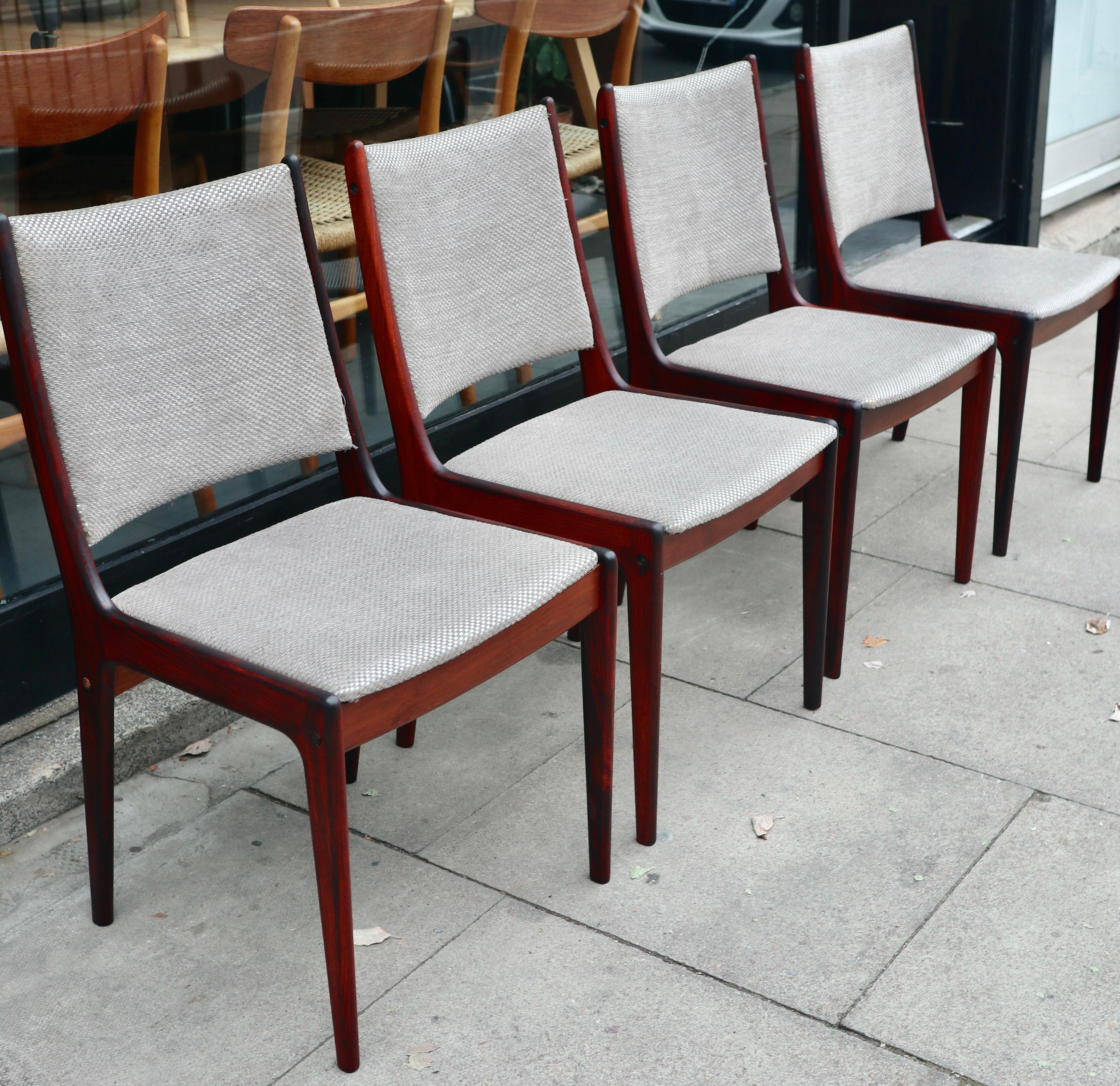 A set of four vintage 1960s rosewood framed dining chairs by Johannes Andersen for Uldum Møbelfabrik. The chairs have been upholstered in quality grey coloured textile and are in  good vintage condition, having been waxed and polished. 