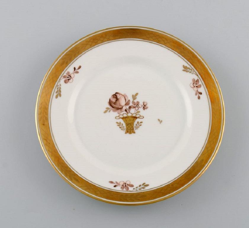 Four Royal Copenhagen Golden Basket plates in porcelain with flowers and gold decoration. Model number 595/9588. 
1960s.
Measure: diameter: 16 cm.
In excellent condition.
Stamped.
1st Factory quality.