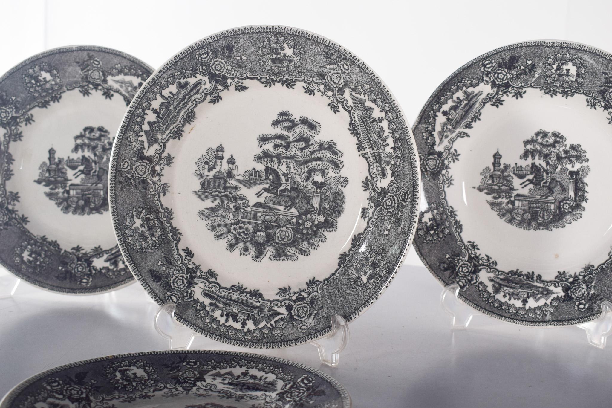 Four Sacavém faience plates ‘Statue, Little Horse’. Decorated in grey on a white background, with a border decorated with a detailed floral pattern, which frames a central scene depicting a bucolic landscape, with trees, buildings and a figure of a