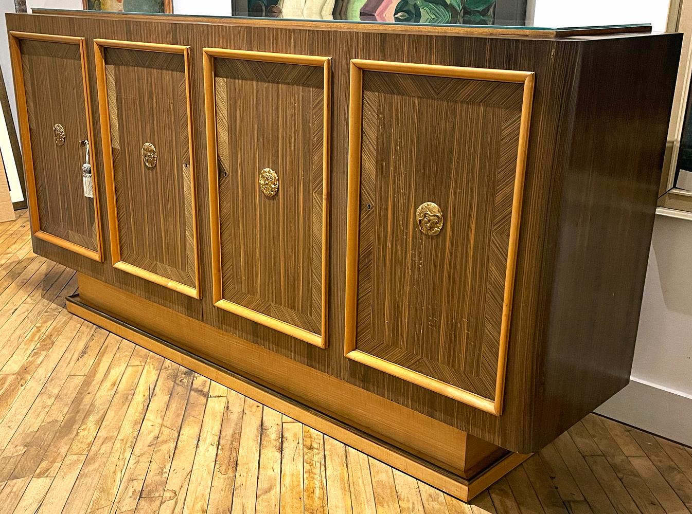 Cleanly designed and beautifully crafted, this 1940s Art Deco sideboard or buffet is finished with gorgeous panels of Macassar ebony veneer, laid in a vertical and diagonal pattern to create a subtle geometric effect on the front side of the piece.