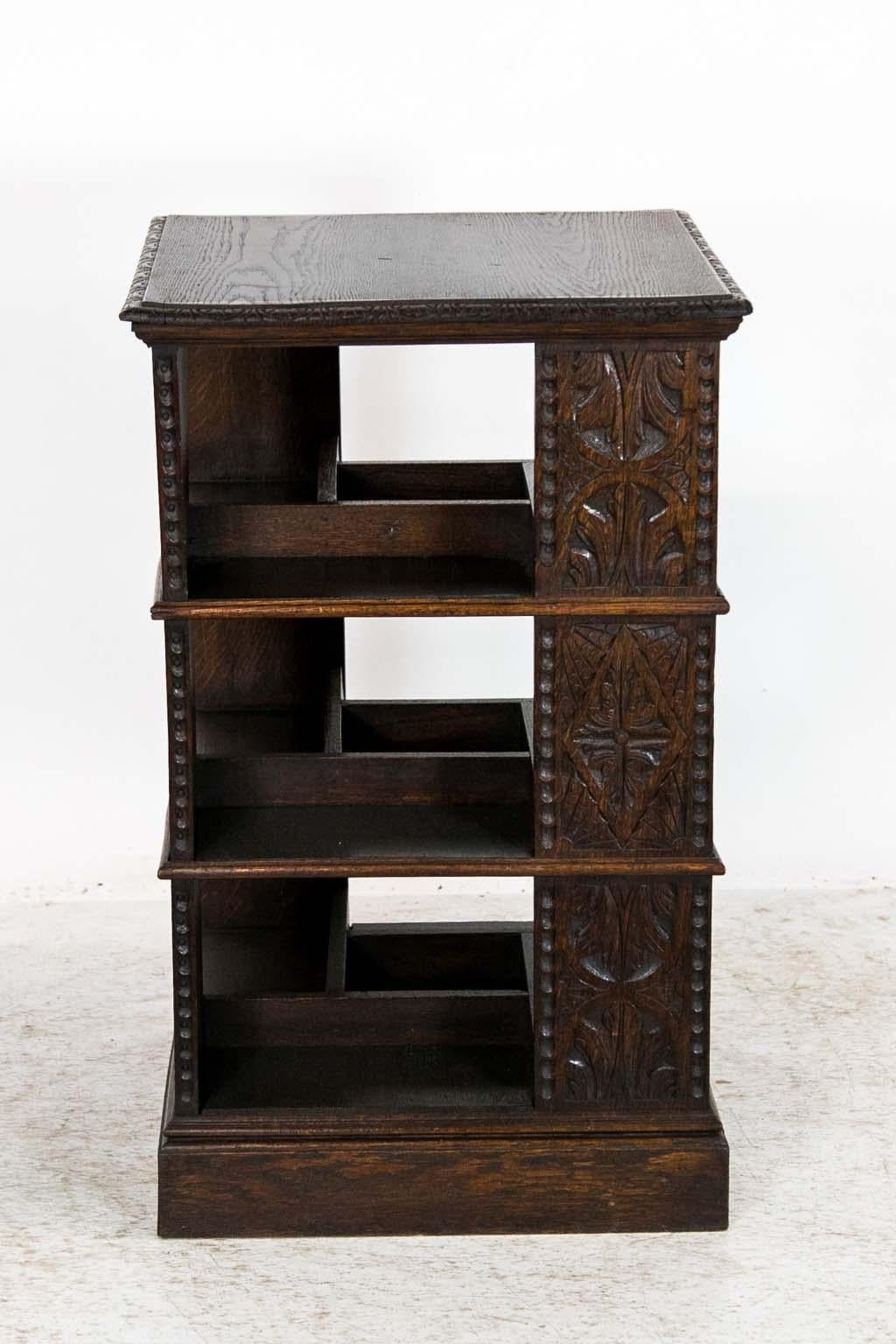 The top of this carved oak bookstand has a carved edge molding. The three support columns on each side are carved with leaves and stylized fans. The shelf dividers have applied shaped moldings.
  