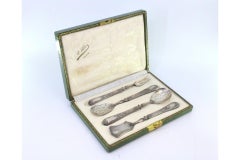 Four silver dessert pieces with cut-out shells and raised floral handles, cased