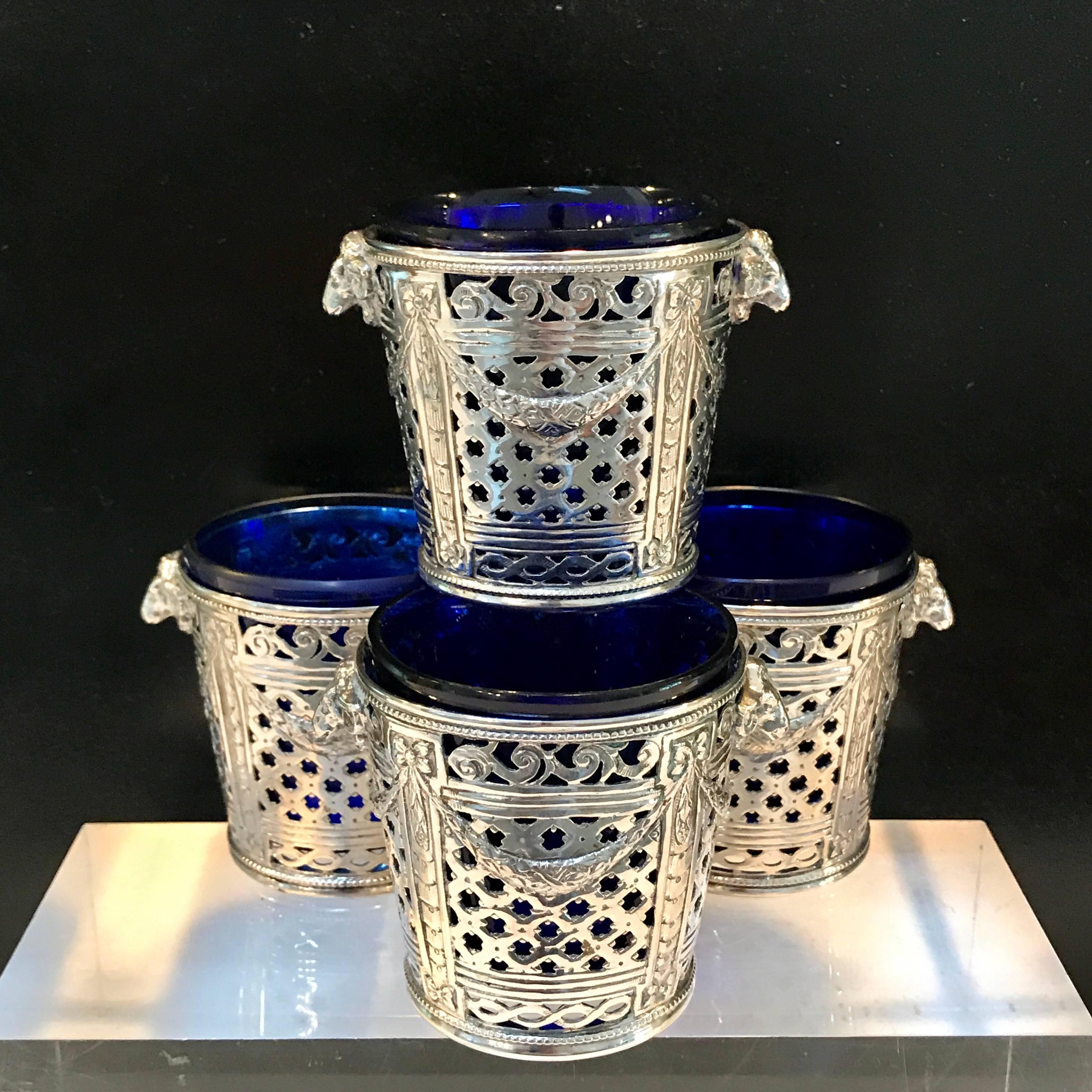 Four silver (.800) Louis XVI style cachepots or salts, with cobalt blue glass liners, each one finely cast and chased with rams head handles and pierced body, with removable cobalt blue glass liner
The liners measure 2.25