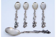 Four silver teaspoons and sugar scoop with reliefs and floral handles