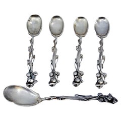 Four silver teaspoons and sugar scoop with reliefs and floral handles
