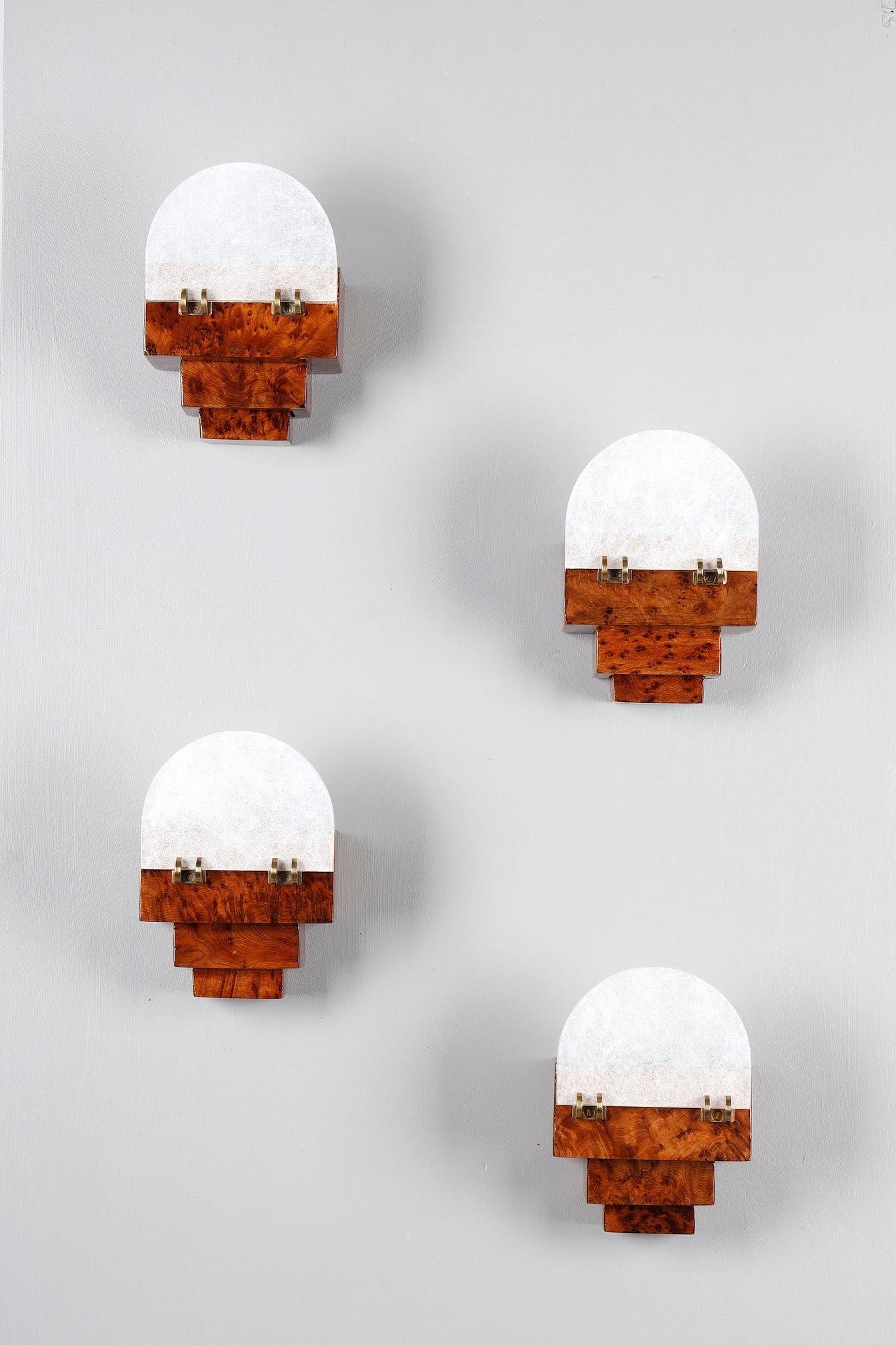 Conjunto de cuatro pequeños apliques de pared de la época Art Déco. Cada candelabro presenta una estructura geométrica escalonada de madera de olmo, resaltada por la elegancia de su veteado natural. El difusor de cristal esmerilado sutilmente