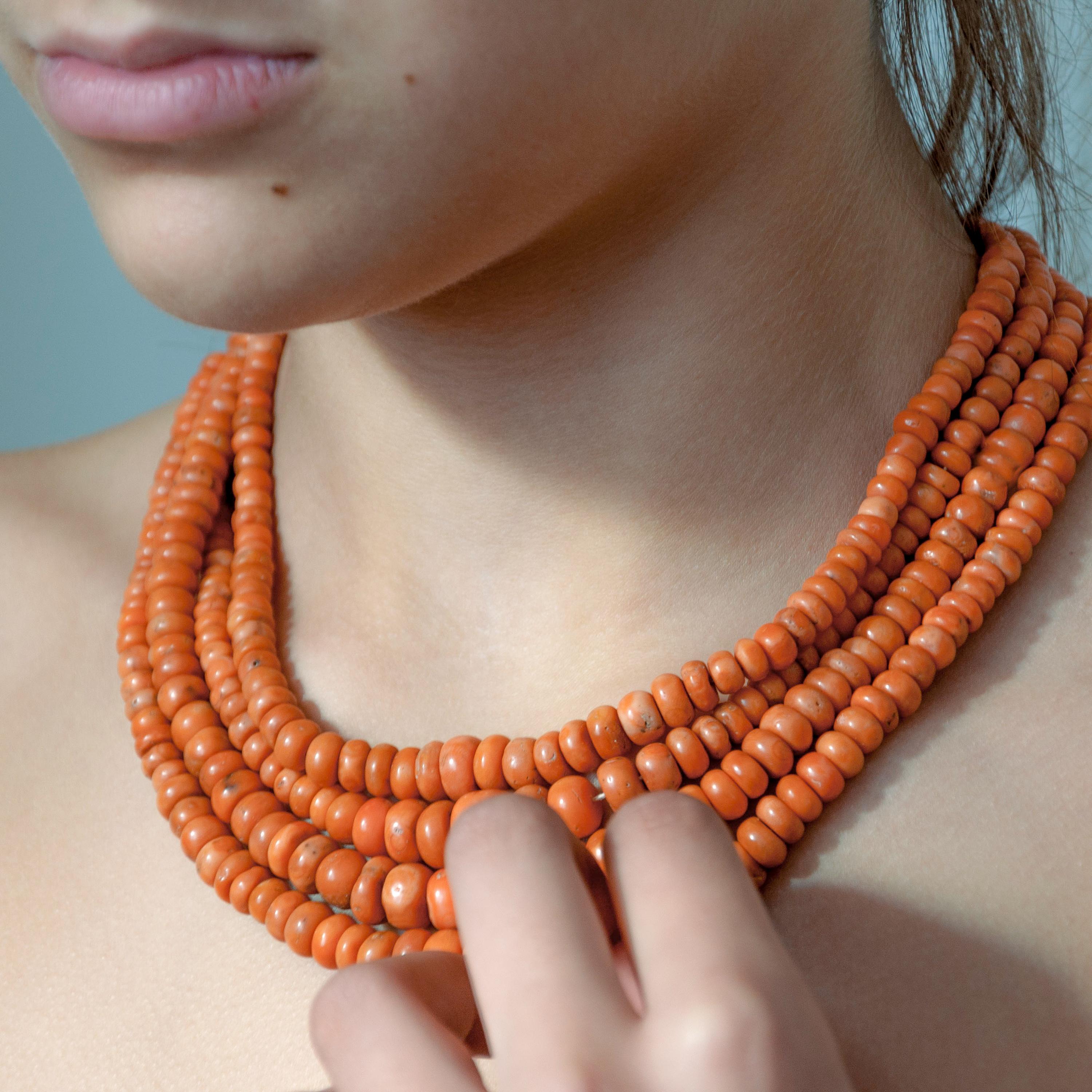 This beautiful and rare four-strand red coral necklace has barrel-shaped corals. The coral expands towards the center of the chain. The coral beads measure approximately between 5 millimeters and 14 millimeters in diameter and descend to the cotton