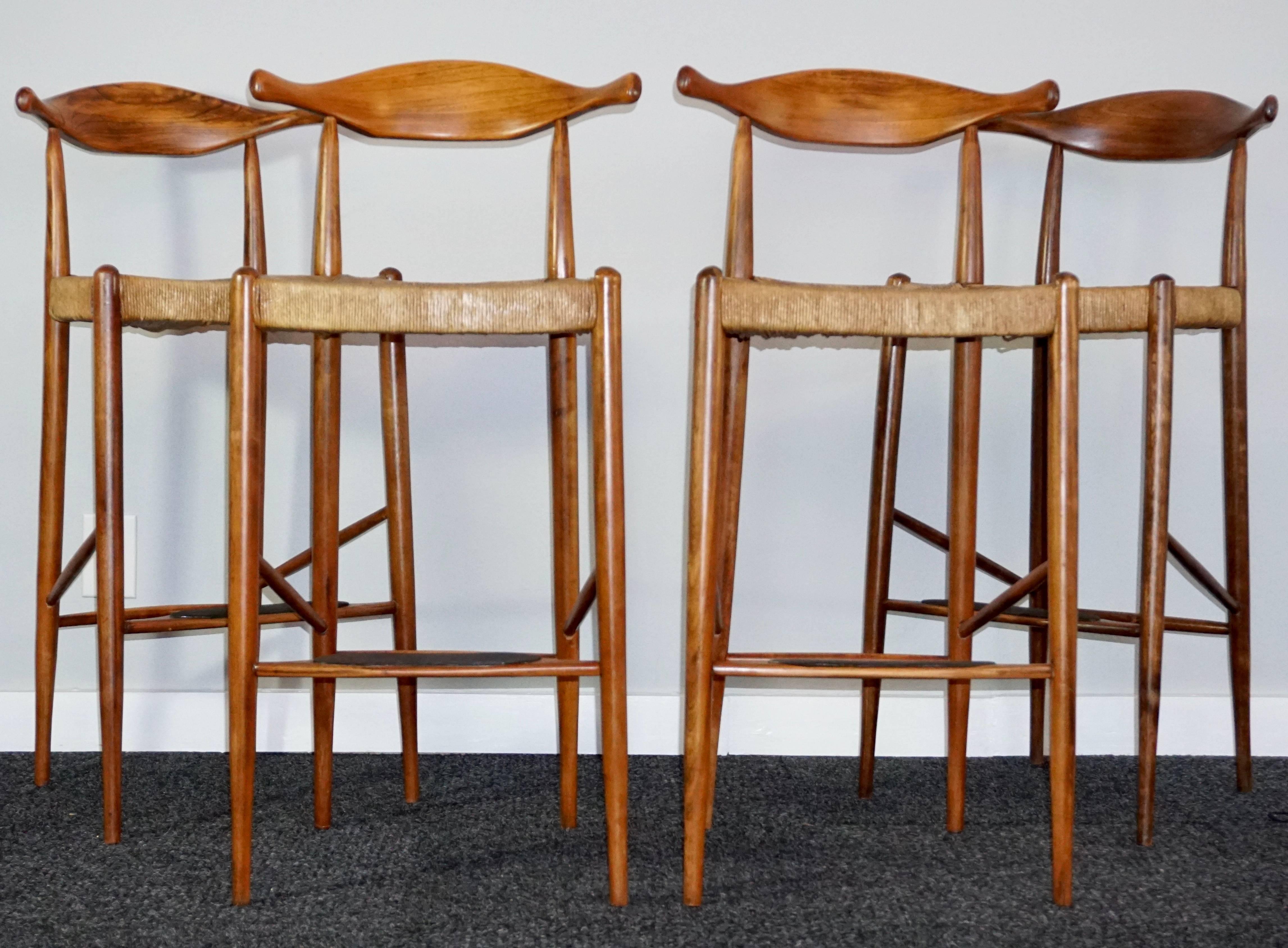 Arthur Umanoff 
Set of four (4) teak and rush rattan seated cow horn stools designed and built in the late 1950s in Denmark by the Umanoff atelier.

Measures: Height 39 inches 
Width 18 inches
Depth 15 inches.

Best known for his chairs and seating