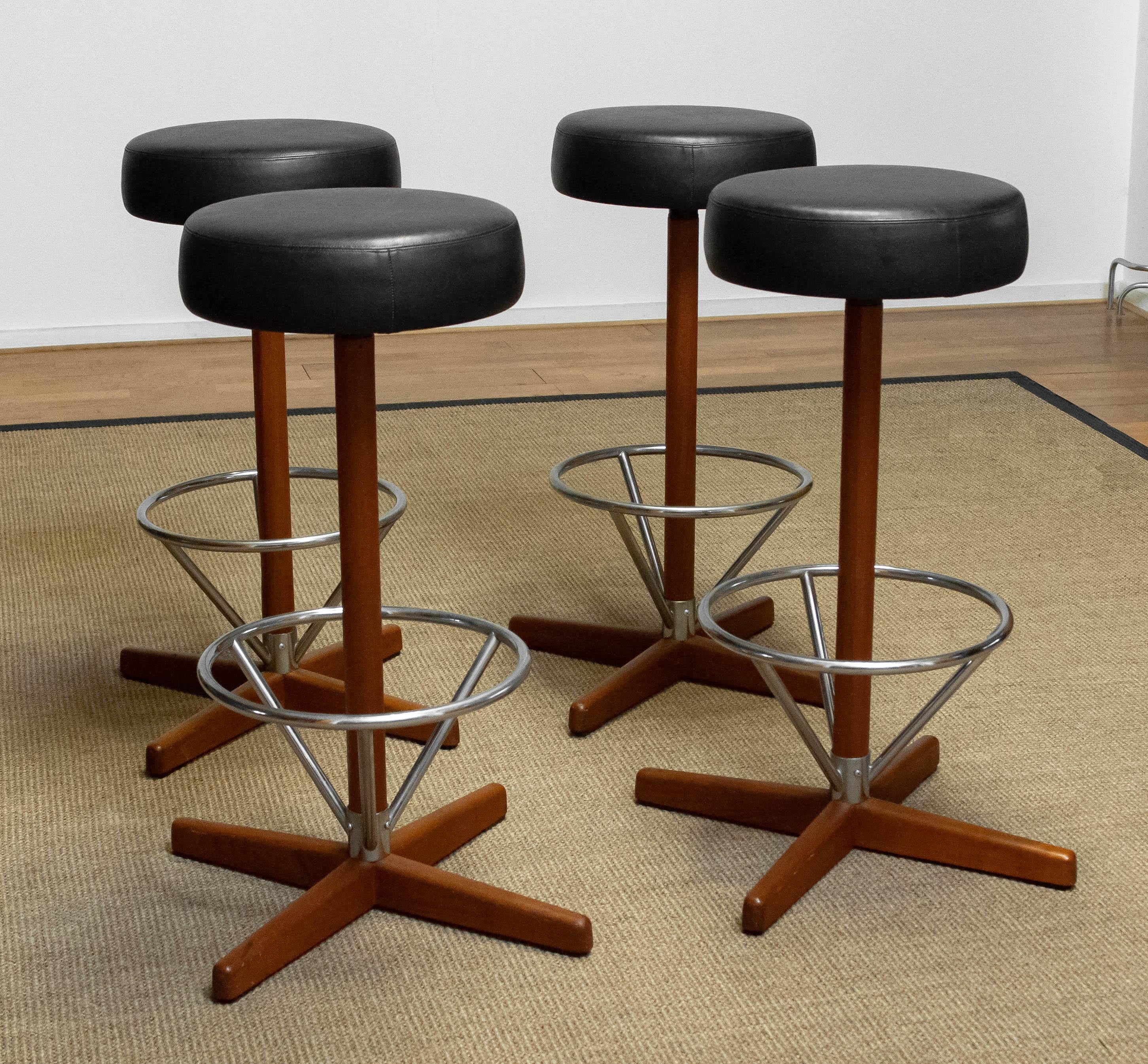 Beautiful group of four teak and chrome swivel bar stools designed by Börje Johanson for Johanson Design upholstered with black faux leather.
All four stools are in good condition.