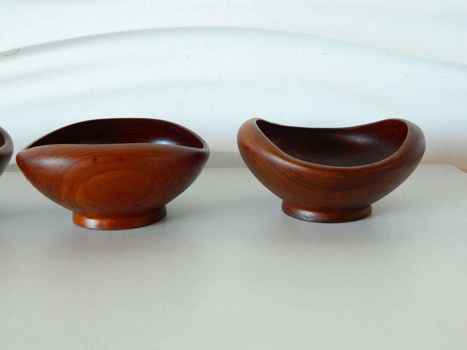 This set of four turned, teak wood bowls have curved edges and footed bases. Reminiscent of Finn Juhl's work for Kay Bojesen.