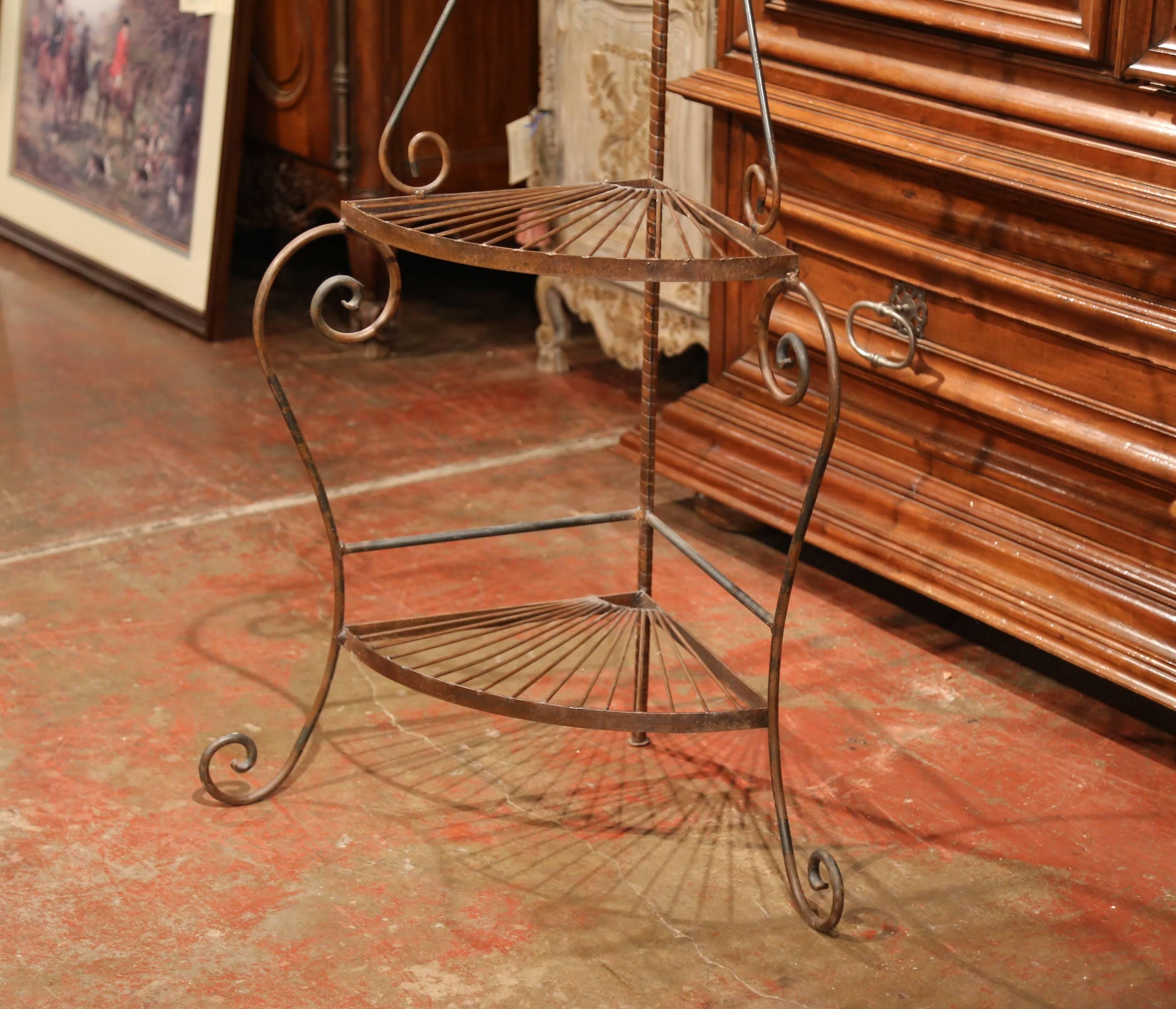 Create more surface space in a living room, study or bedroom with this interesting and useful corner shelf. The display piece made of iron stands on three curved feet and features four shelves. The piece is in excellent condition and adorns a rusty
