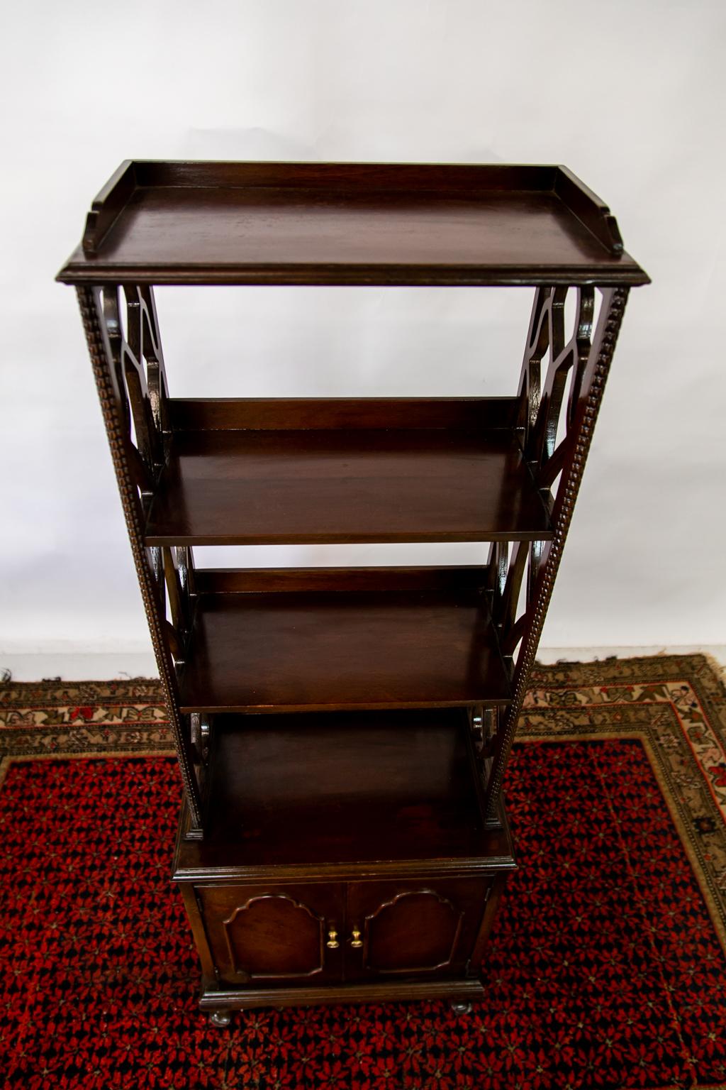 The upper shelf section of this English shelf/ cupboard has open trelliswork side supports. The top has a shaped gallery and molded edge. There is carved beading on the front edge of the side supports.