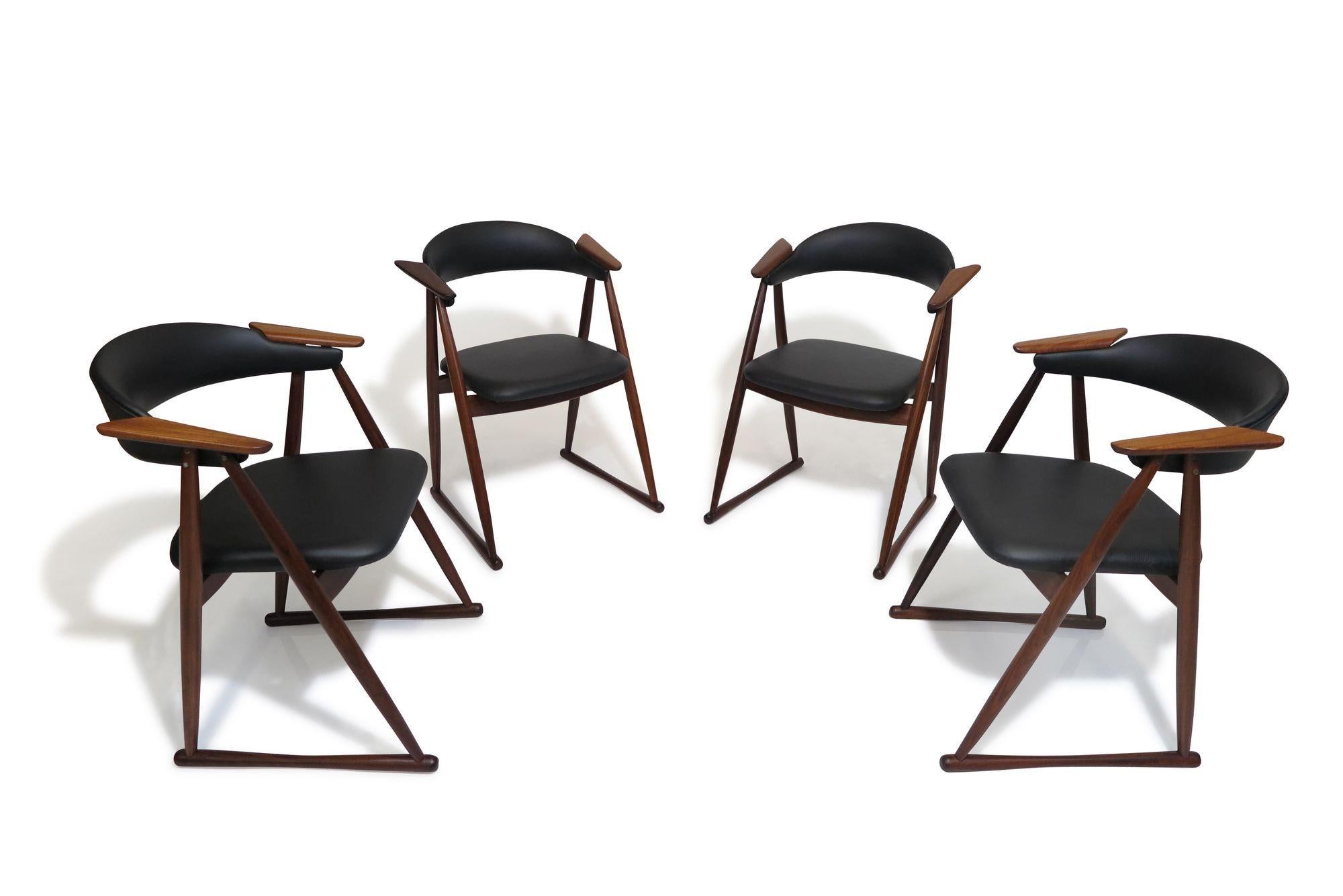 These rare teak dining chairs, crafted in Scandinavia during the late 1960s, feature solid teak frames with upholstered seats, curved backs, and distinctive floating wood arms. Recently professionally restored and upholstered in new black leather,