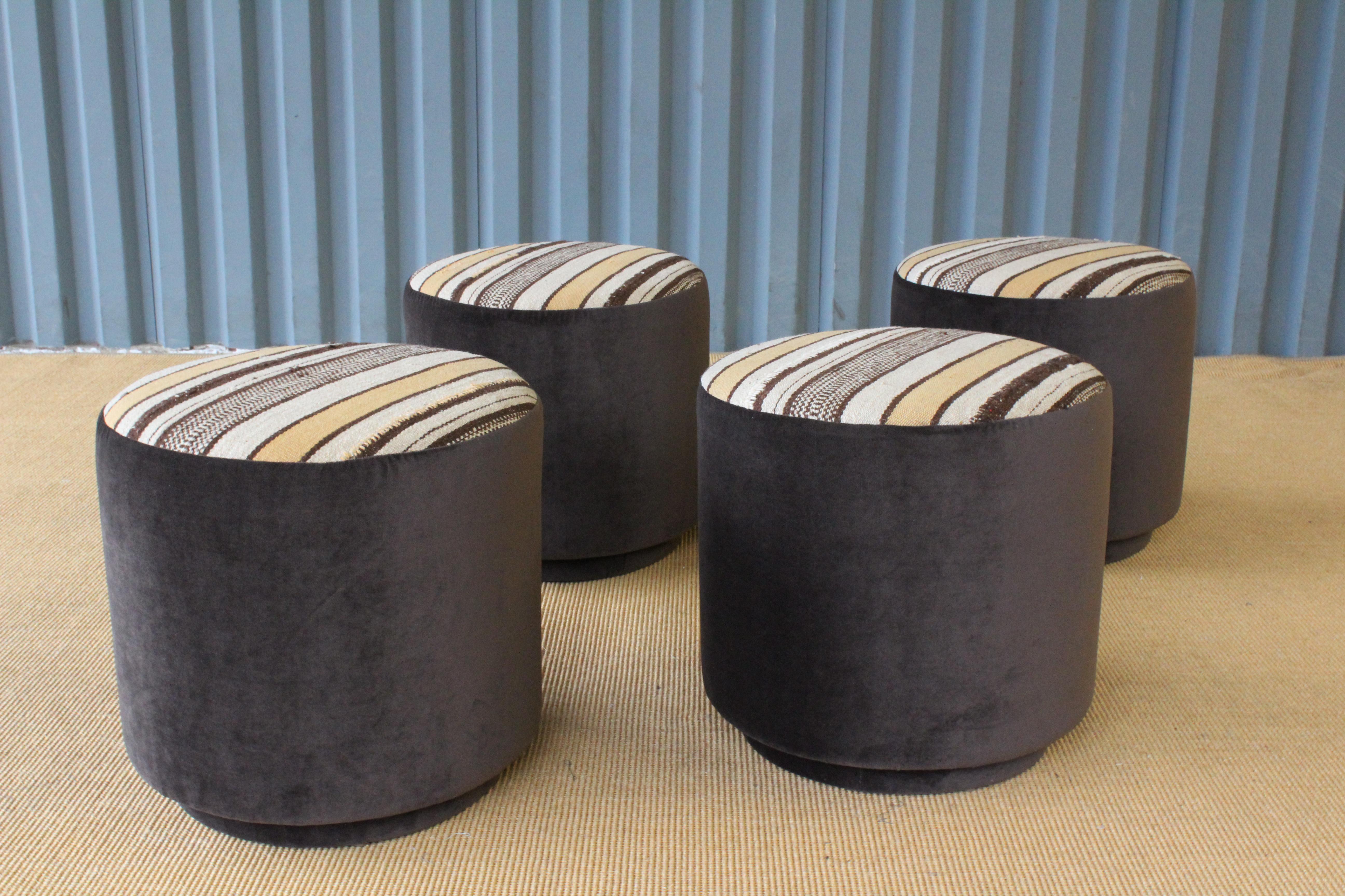 Three stools upholstered in a vintage flat-woven striped rug and brown velvet. They sit on an upholstered base. Sold individually.