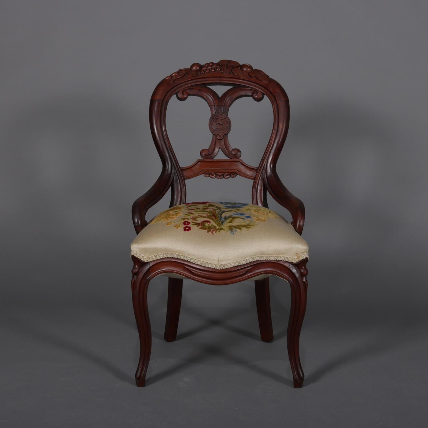 Set of 4 antique Victorian side chairs feature balloon backs with carved berry and foliate crests and opposing C-scroll back slats, seats with floral embroidered crewel upholstery, circa 1890.

Measures: 35.5