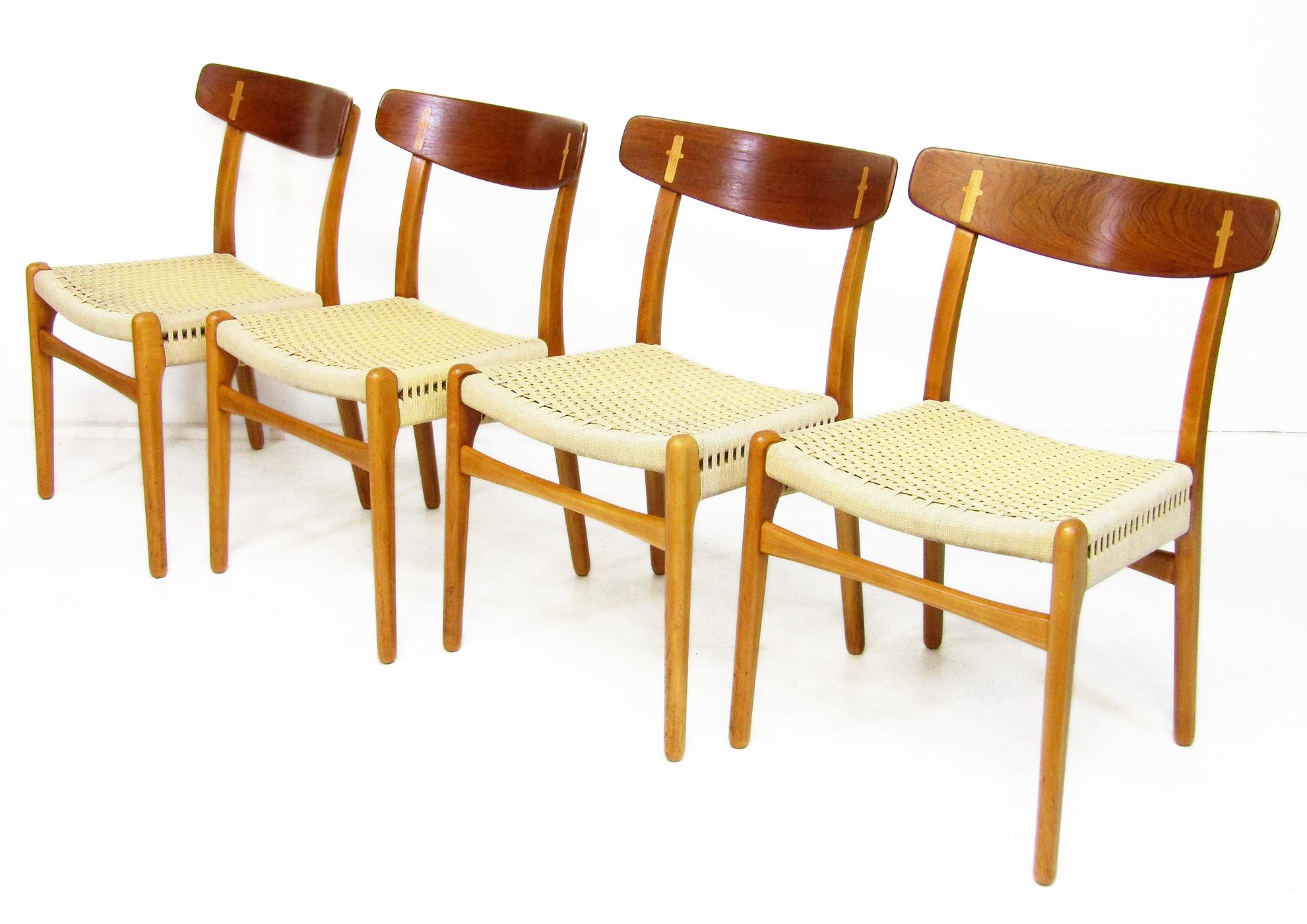 A set of four wonderful 1950s CH-23 dining chairs by Hans Wegner for Carl Hansen.

In teak, beech and oak they feature eye-catching oak joinery in the teak backrests. The success of the design puts them amongst Wegner's more sought-after dining