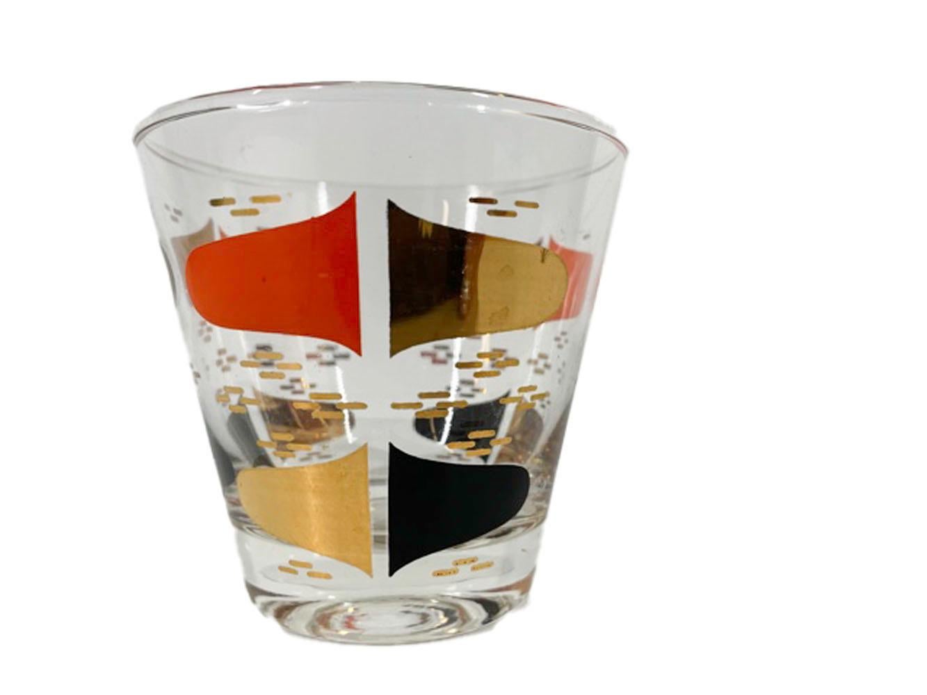 Set of 4 Atomic period old fashioned glasses with split black, orange and gold ellipses among a background of gold dashes on clear glass.