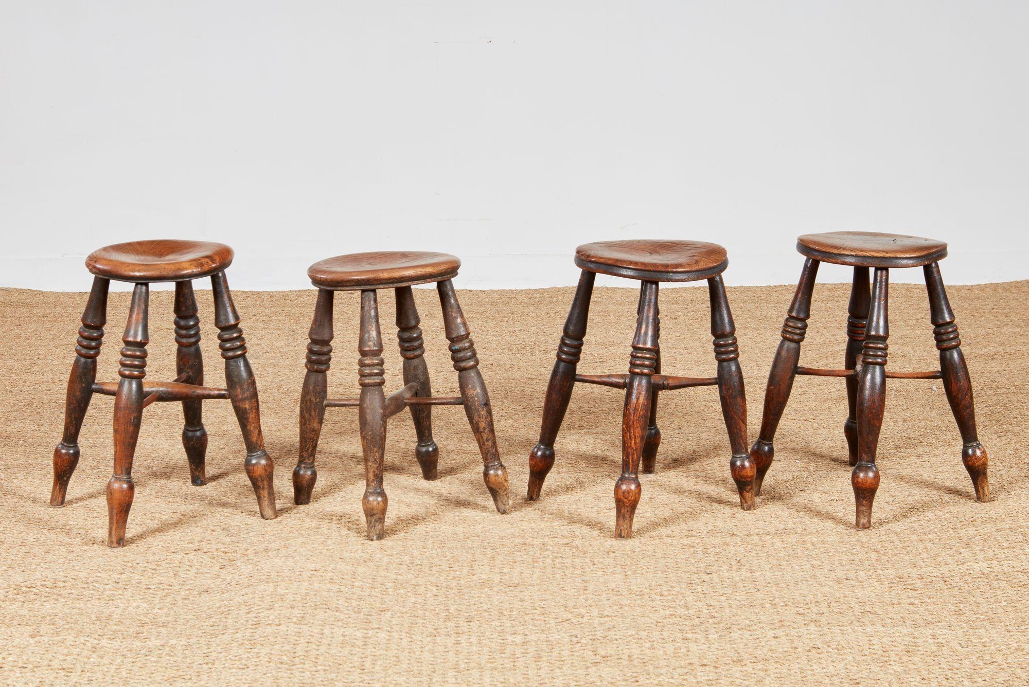 Four attractive windsor dairy stools in elm and oak each with a round dished top with molded edge on four ring-turned turned legs ending in bulb feet joined by pierced cross stretchers. Tops with undulating forms characteristic of old elm. Stool
