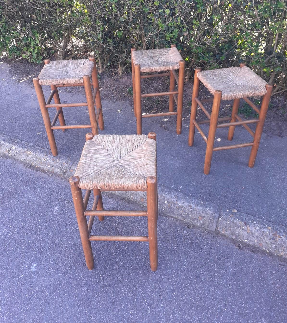 Four wood and straw high stools.