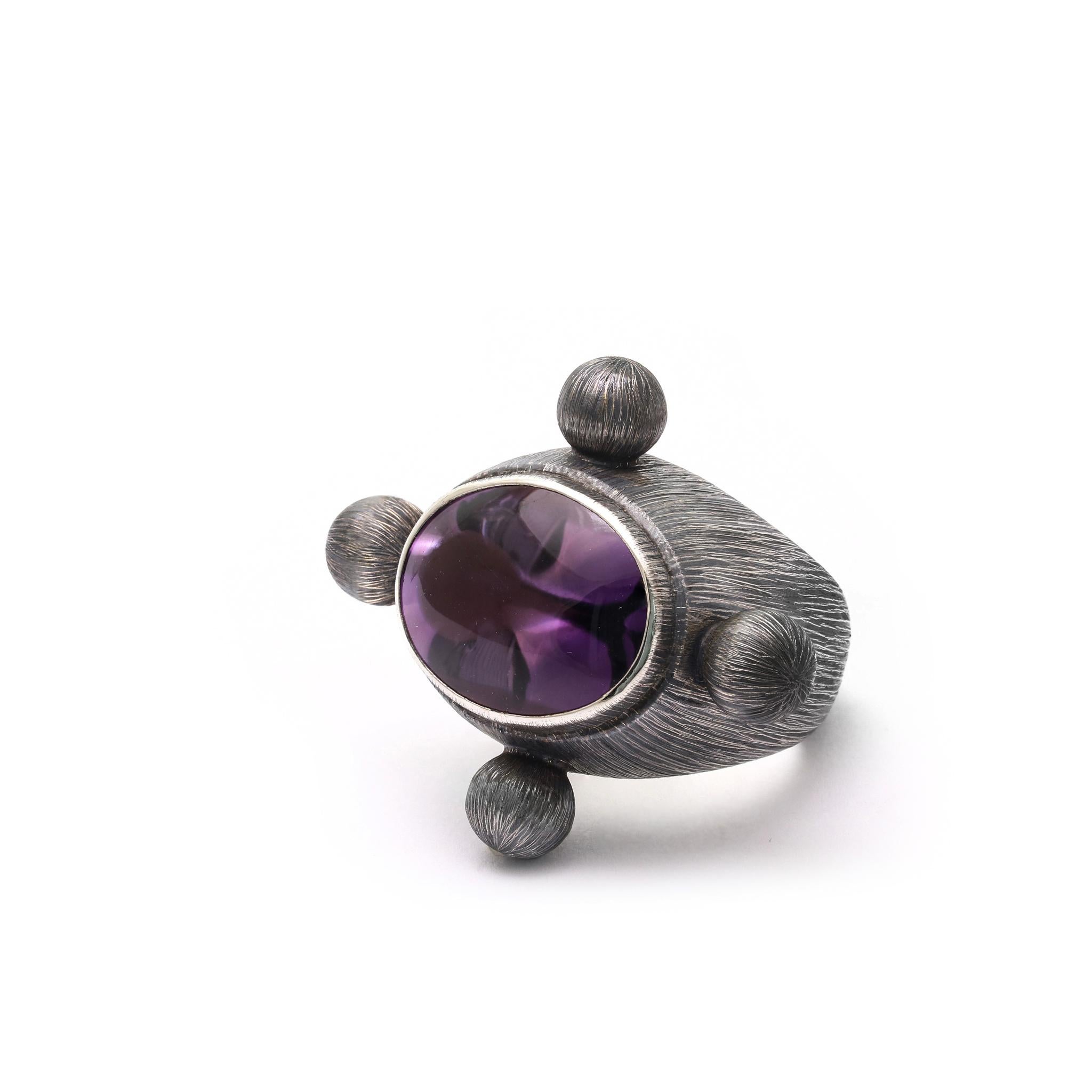 Quattro sfere d'argento inciso che ruotano intorno al colore rifrangente della pietra all'interno.
925 Argento Sterling inciso e ossidato
Incastonato con ametista o quarzo fumé 1,8 x 2,5 cm.
Dimensioni dell'anello: 1,18