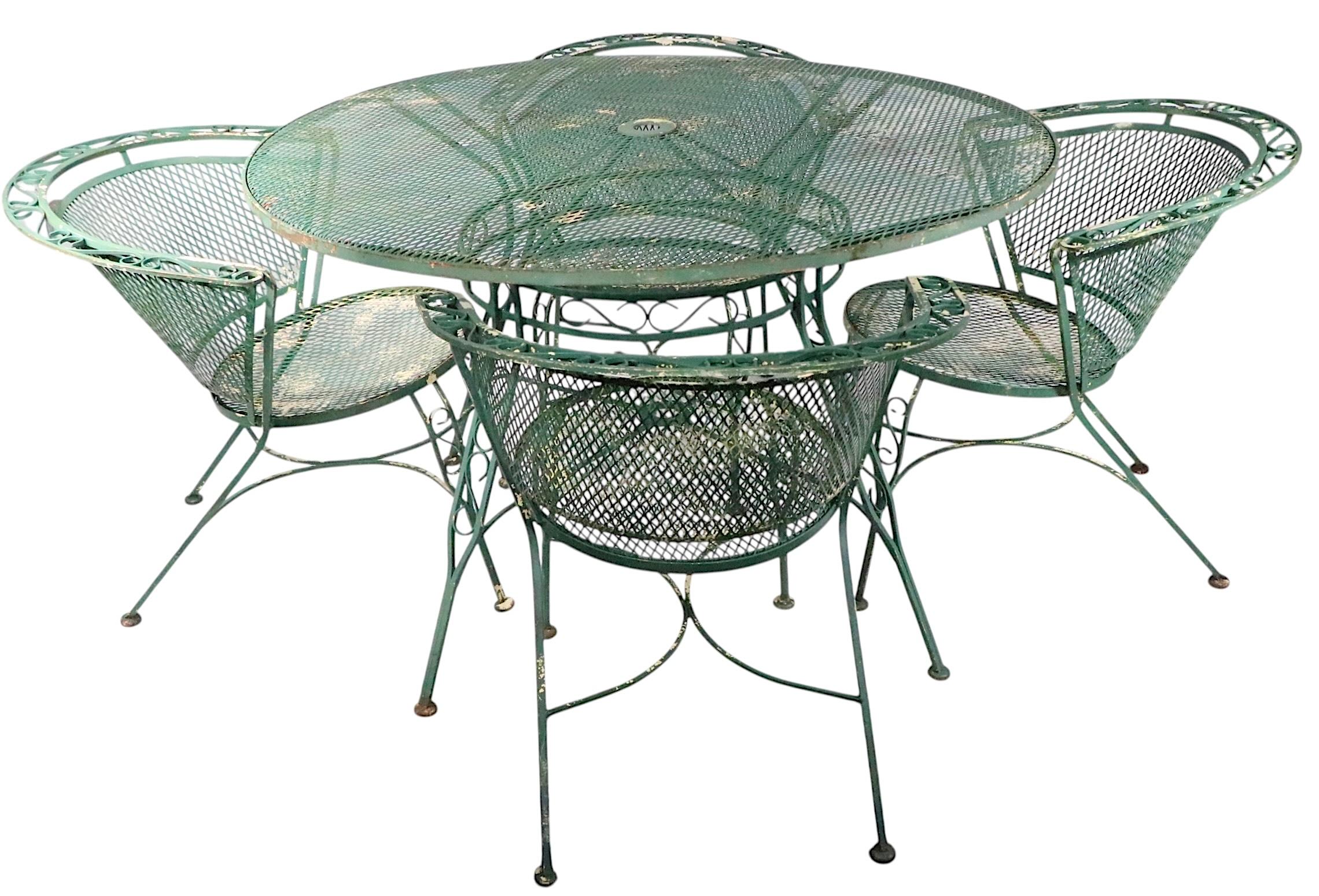 Juego de cuatro comedores de hierro forjado y malla metálica para jardín, patio o piscina  sillas de Salterini. Las sillas presentan respaldos curvados de malla metálica envolvente y asientos de malla metálica, con ribetes decorativos de hierro