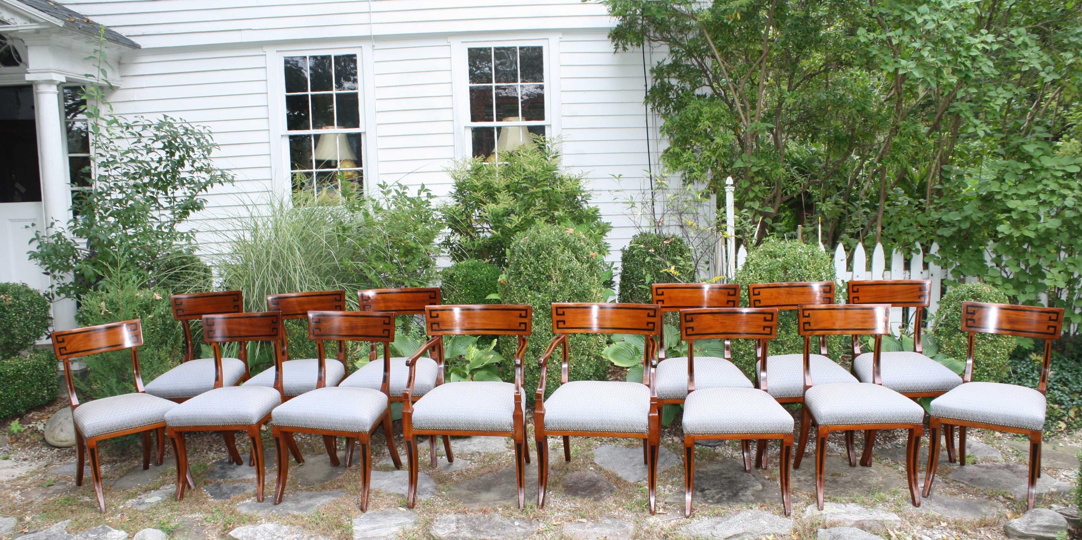 Set of fourteen English Regency period ebony inlaid dining chairs of Greek klismos form.
2 armchairs and 12 side chairs, of light honey-colored mahogany.  Serviceable upholstery if compatible with present decor.  Acquired from Hyde Park Antiques,