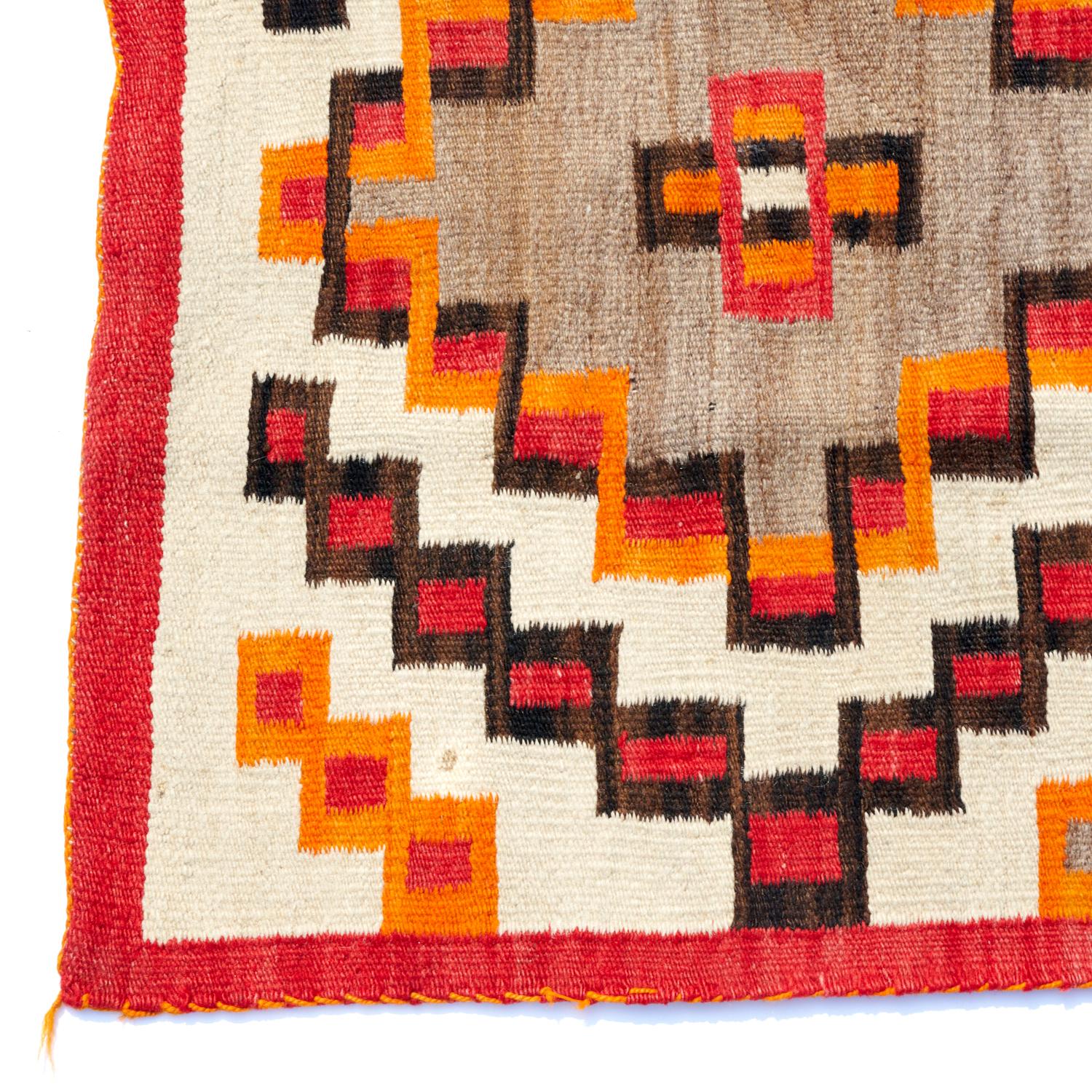 A striking Navajo Fourth Phase rug/wall hanging. Heavy, densely woven wool in a red, black and orange geometric pattern on a cream and brown/grey ground, with orange edging. Lazy lines, a wool warp and side selvage cord are all hallmarks of Navajo