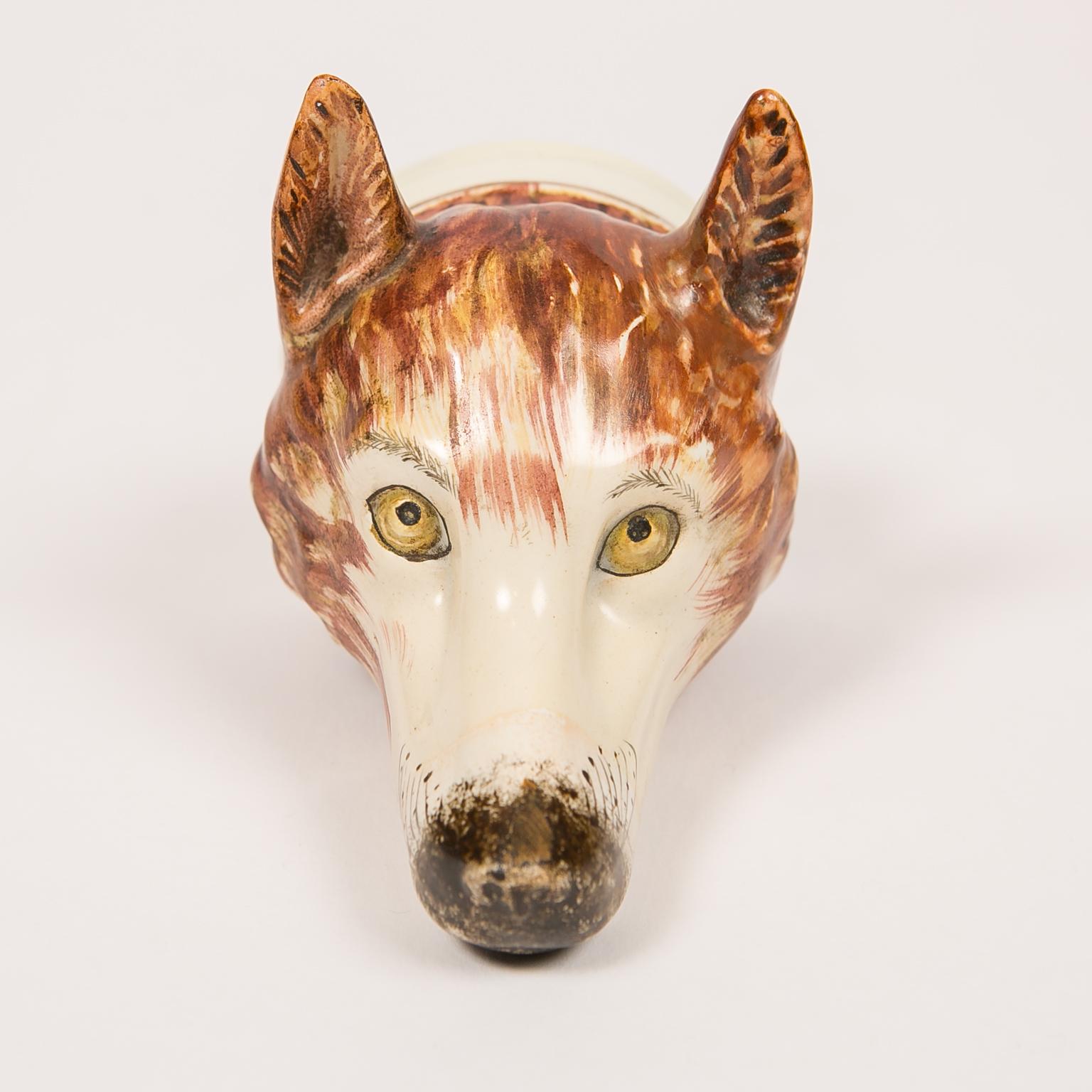 A Staffordshire pottery fox head stirrup cup deaccessioned from Colonial Williamsburg. The cup has its stock number and 