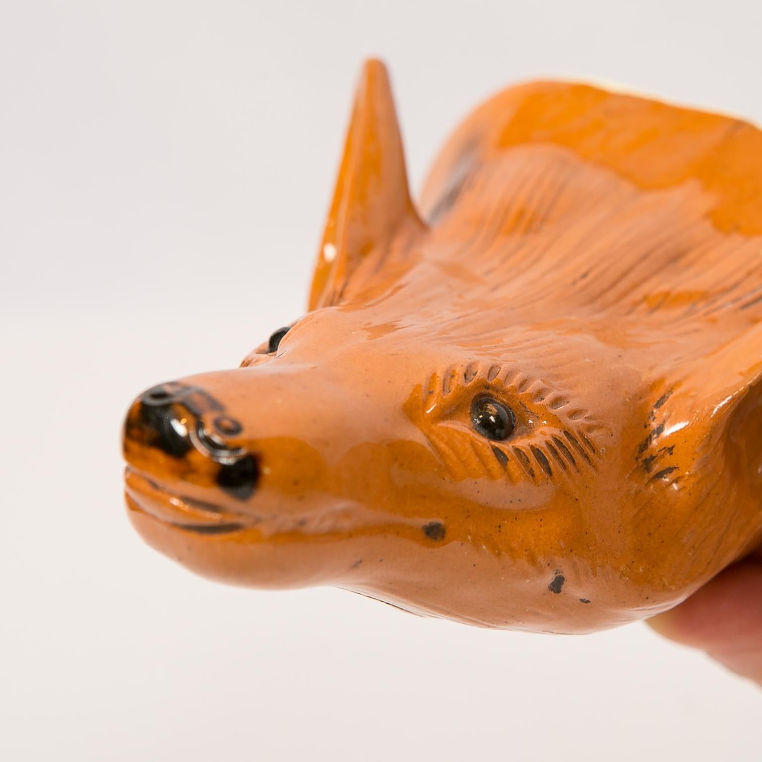 A fine antique Staffordshire pottery fox head stirrup cup. Deaccessioned from Colonial Williamsburg. Made circa 1790. Molded in the style of Ralph Wood, this fox head stirrup cup is painted in bright orange with brown details. Interesting features