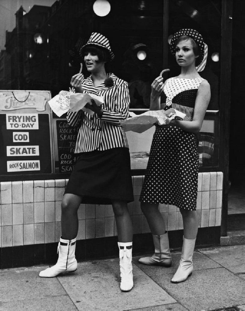 "Fish And Chips" by Fox Photos

Standing outside the fish and chip shop in two items from the Lee Cecil 'Jetsetters' collection are Jackie Bowyer, left, and Judy Gomm, right.

Unframed
Paper Size: 40"x 30'' (inches)
Printed 2022 
Silver Gelatin