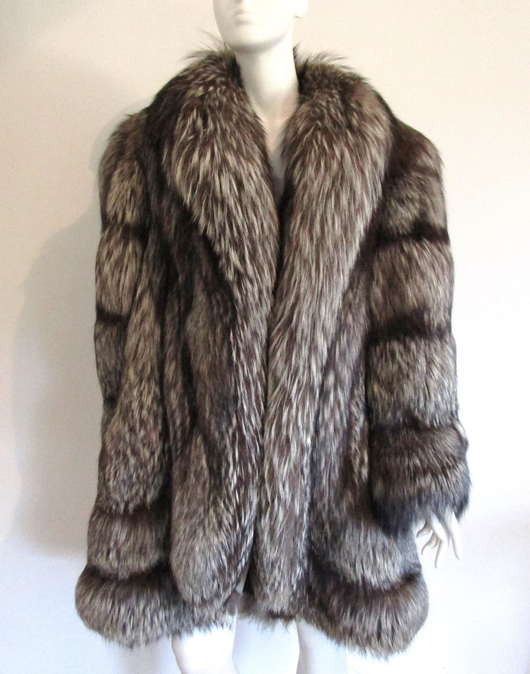 This will not disappoint, stunning Silver Fox Coat. Appears to have never been worn. Stunning scalloped edges on the bottom front of the jacket. Has a Fabulous swing to the back. 2 pockets 1 hook and eye closure. Soft and supple. Measuring up to a