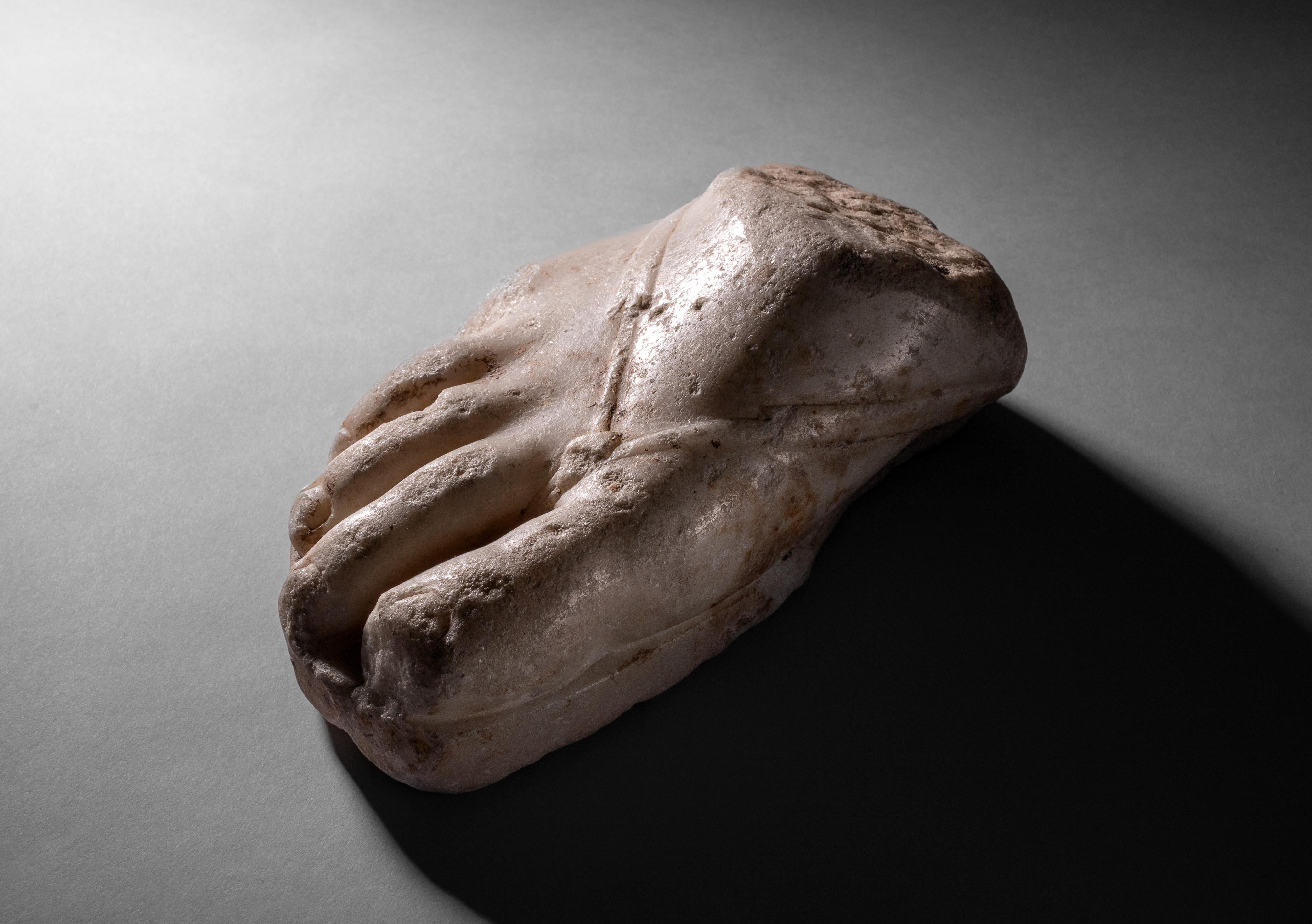 Roman marble Fragment of a Right Foot with Sandal
Circa 1st - 2nd Century A.D.

An evocative Roman marble fragment, preserving the front portion of an over-lifesized sandalled foot. The toes, nails, and bridge of the foot have been sensitively