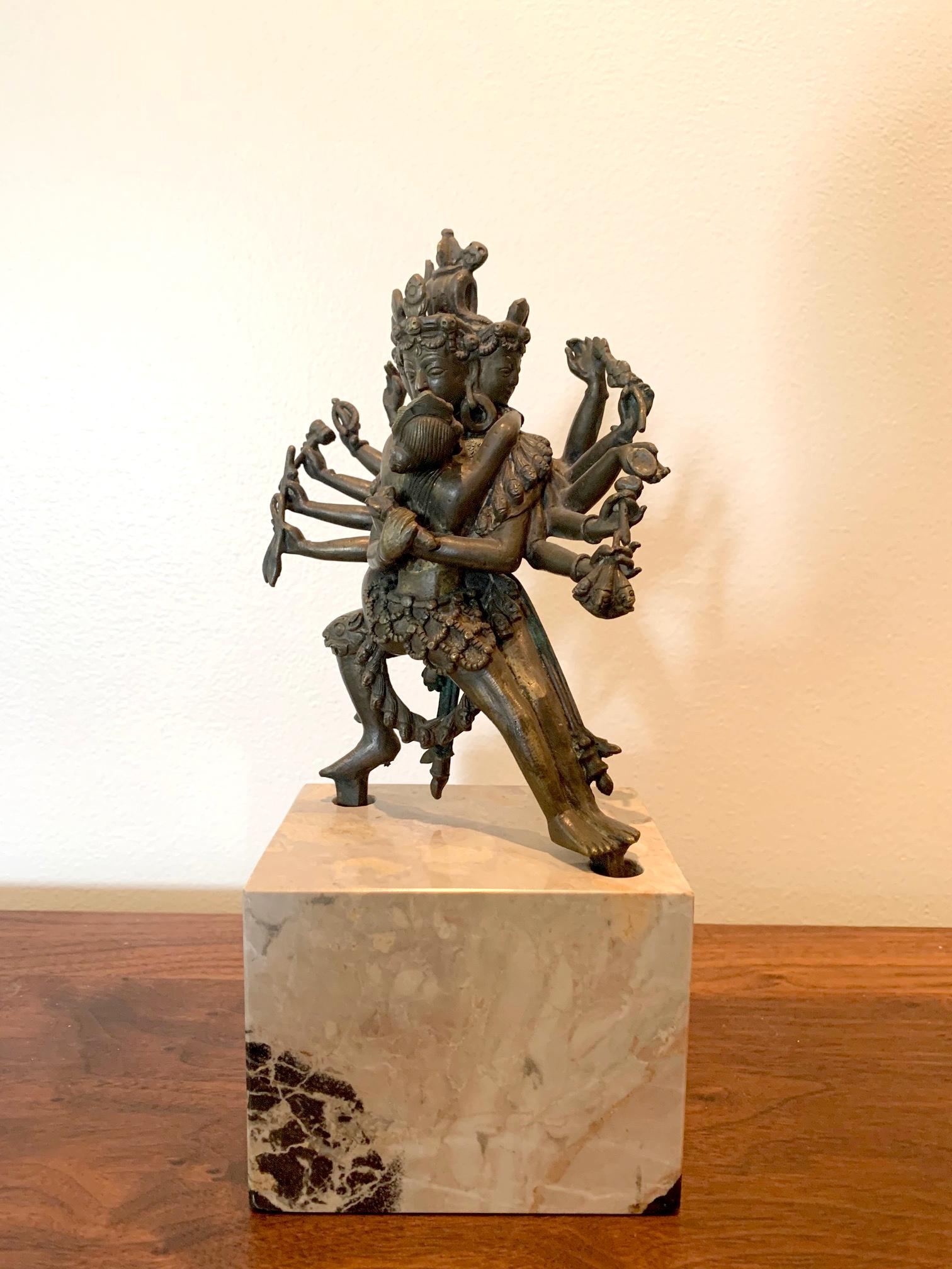 A small cast bronze statue of Yamantaka and his envisioned consort Vajravetali. It is the main fragment of a larger sectioned piece with the lotus base missing. A marble cube base was used to display the small statue. It is from Tibet, circa end