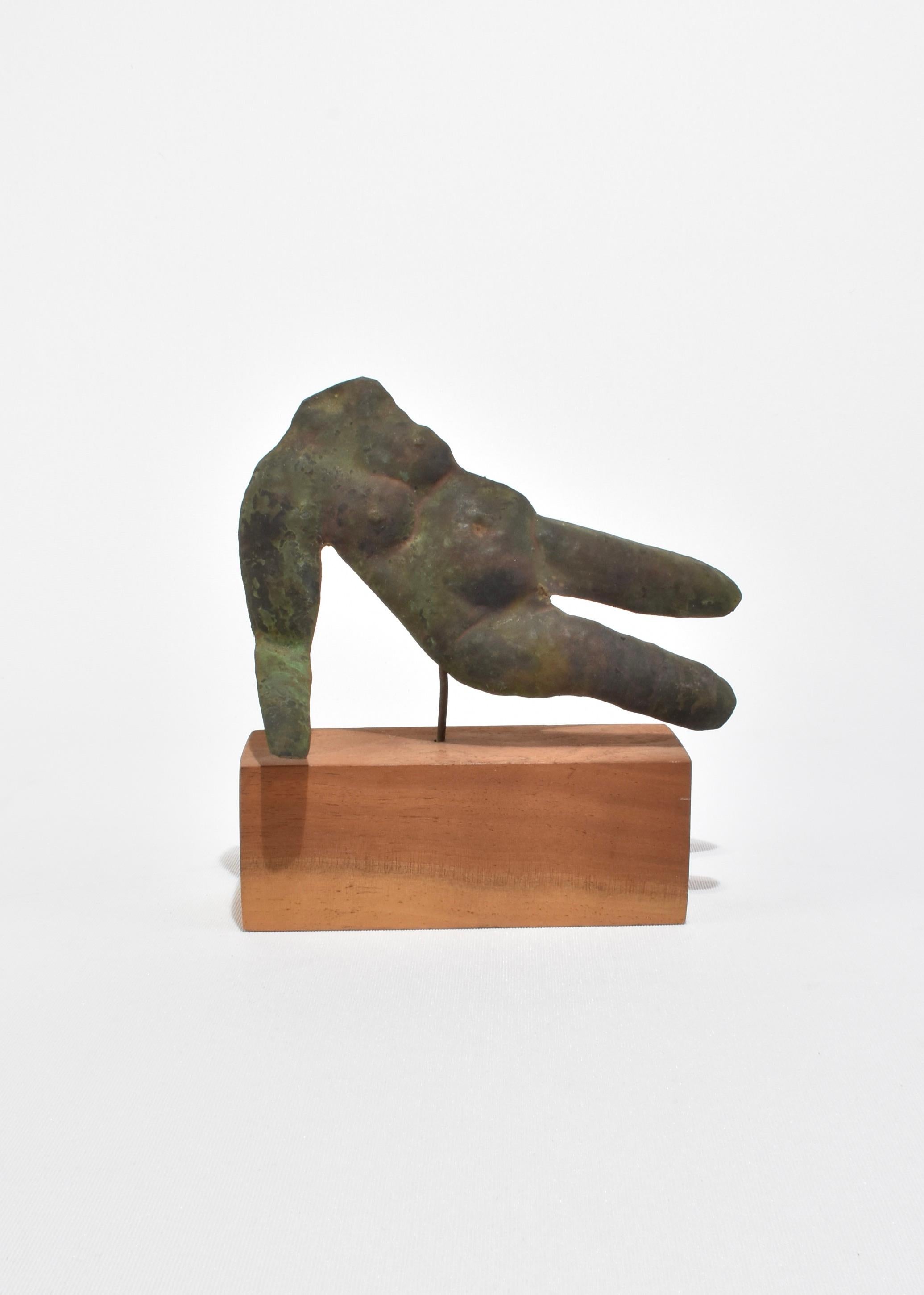 Evocador torso de metal hecho a mano, patinado en un intenso negro verdoso con matices moteados de cobre y verdín. Montada sobre un zócalo de madera tallada a mano, su asimetría y textura la hacen parecer antigua y moderna a la vez.