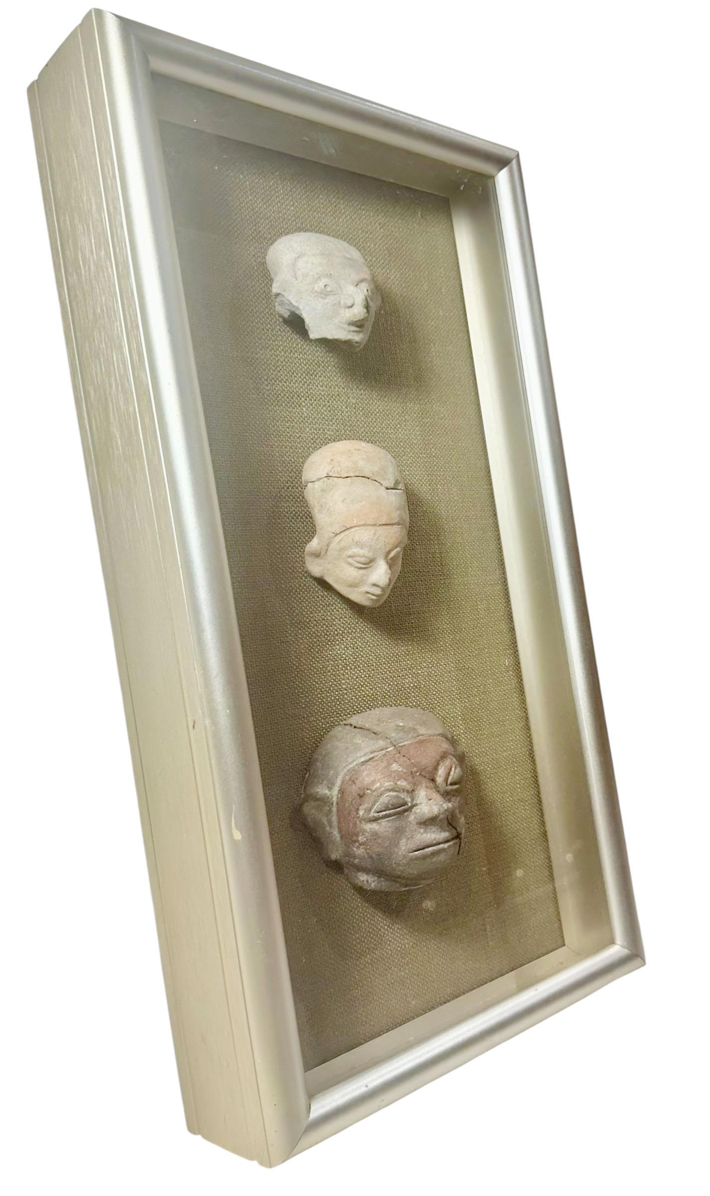 A rare set of three Olmec Pre-Columbian fragments, dating to the 15th century, presented in a modern shadowbox display. Each fragment offers a glimpse into the artistry and cultural significance of the Olmec civilization, one of the earliest and