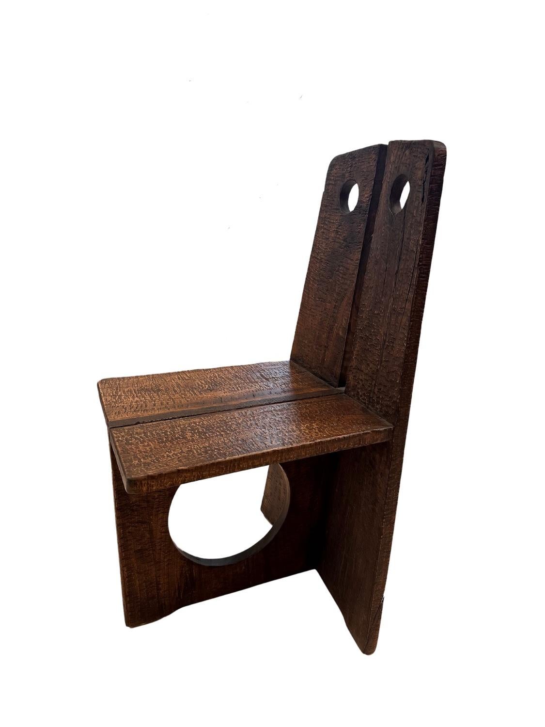 Crafted from fragrant camphor wood, known for its distinctive aroma and beautiful grain patterns. The chair's minimalist design features two vertical backrests with circular cutouts, adding a touch of modernity to its rustic charm. The seat is flat