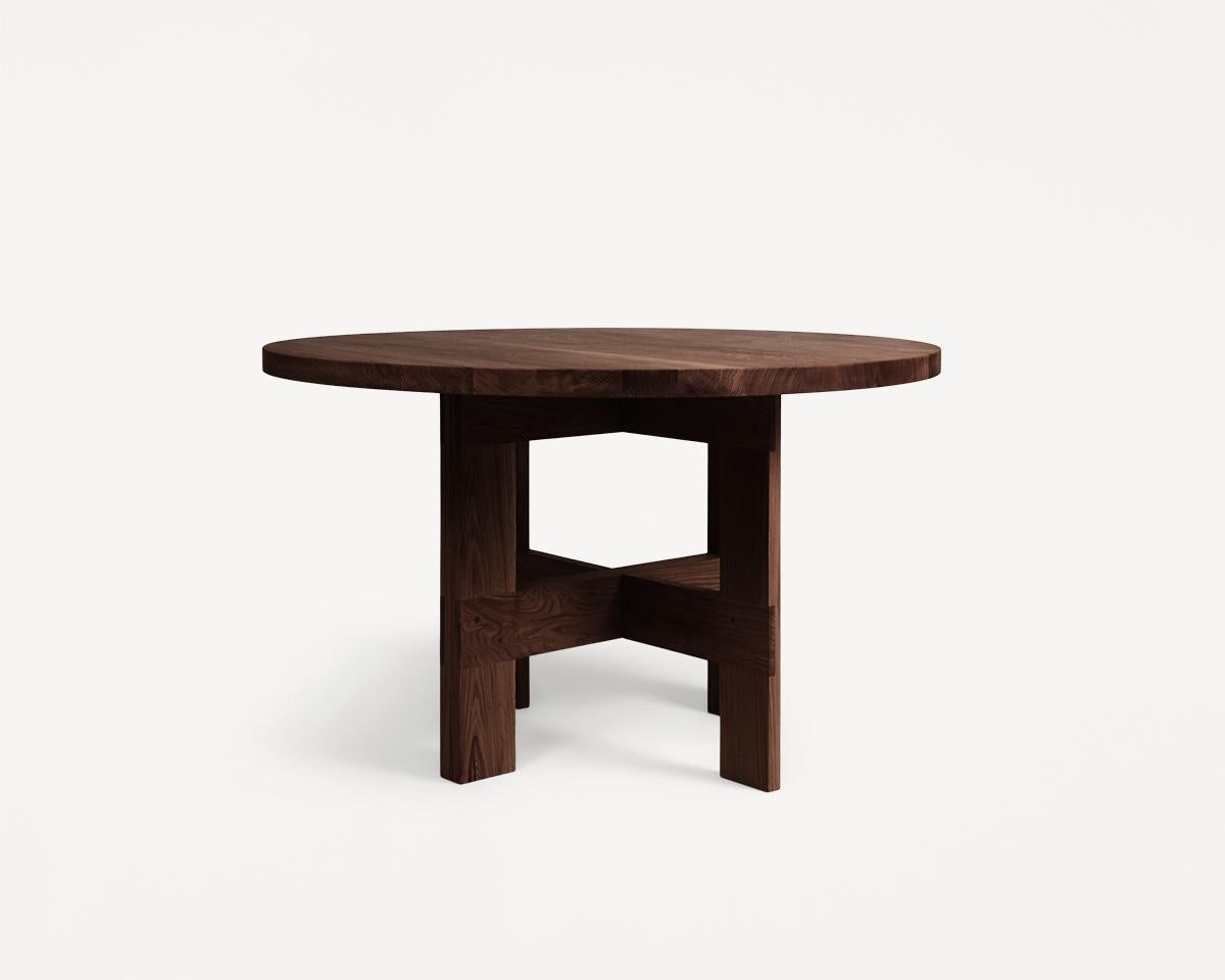 The Farmhouse Trestle Table Round in dark oak features a rich, deep tone. Crafted in high-quality solid oak, supported by trestles, and inspired by traditional farmhouses with a rural aesthetic. This wooden dining table serves as a focal point in