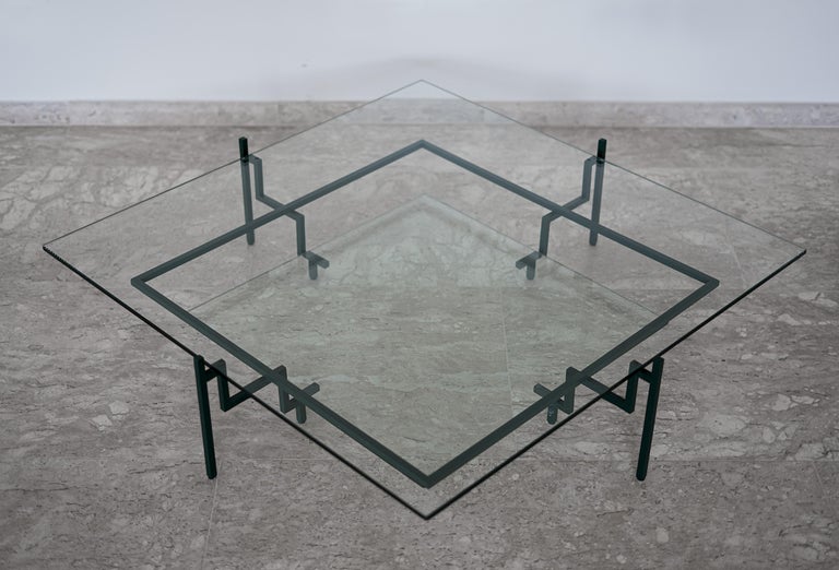This award-winning minimalist steel and glass showcase table is designed within architectural and geometric reasoning. With square DNA, four stair-shaped supports are connected by an intermediate-height bead to establish a balancing and support