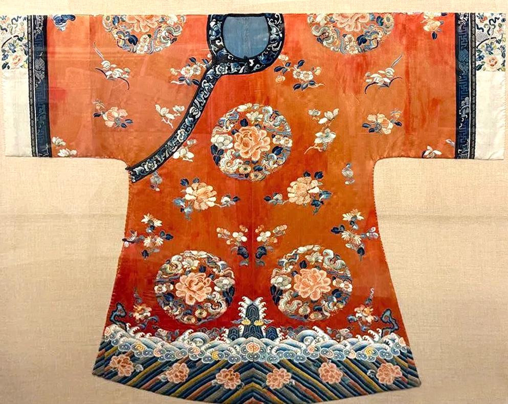 Manteau de cour de femme en fine soie orange à larges manches de la dynastie chinoise Qing (milieu du XIXe siècle), monté sur une toile de lin et présenté sous une boîte d'ombres en plexiglas avec des garnitures d'angle en laiton. Le manteau mi-long