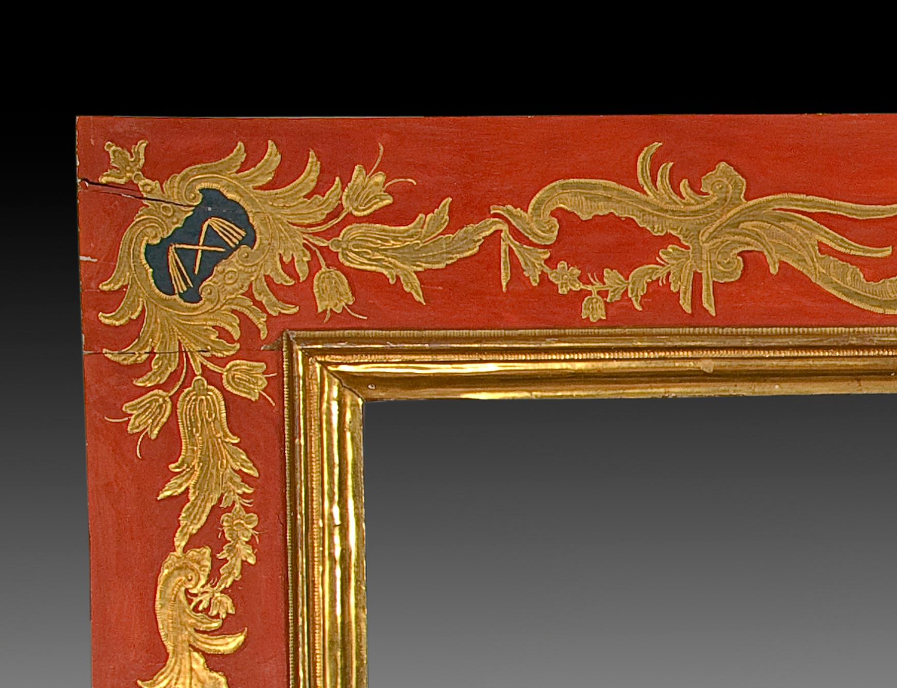 Polychrome and gilded wood frame. Late 18th century.
Rectangular frame with golden seed beads on a red background and elements related to the Passion of Christ in shields in the corners and center of the longest sides: dice, nails, bag (of the Judas
