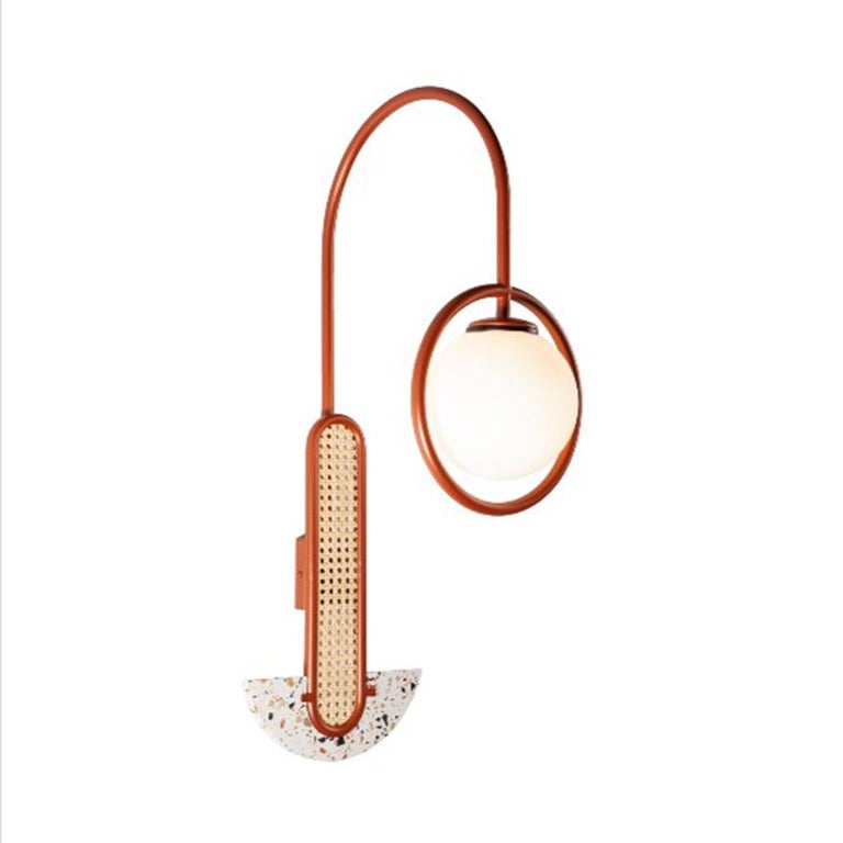 Frame Wall Sconce stands out for its strong shapes made of Terrazzo stone, with frosted glass globes kindly wrapped by a smooth, curved lacquered metal structure. In its Post Modern style, it is original as a sculptoric shape that embraces soft