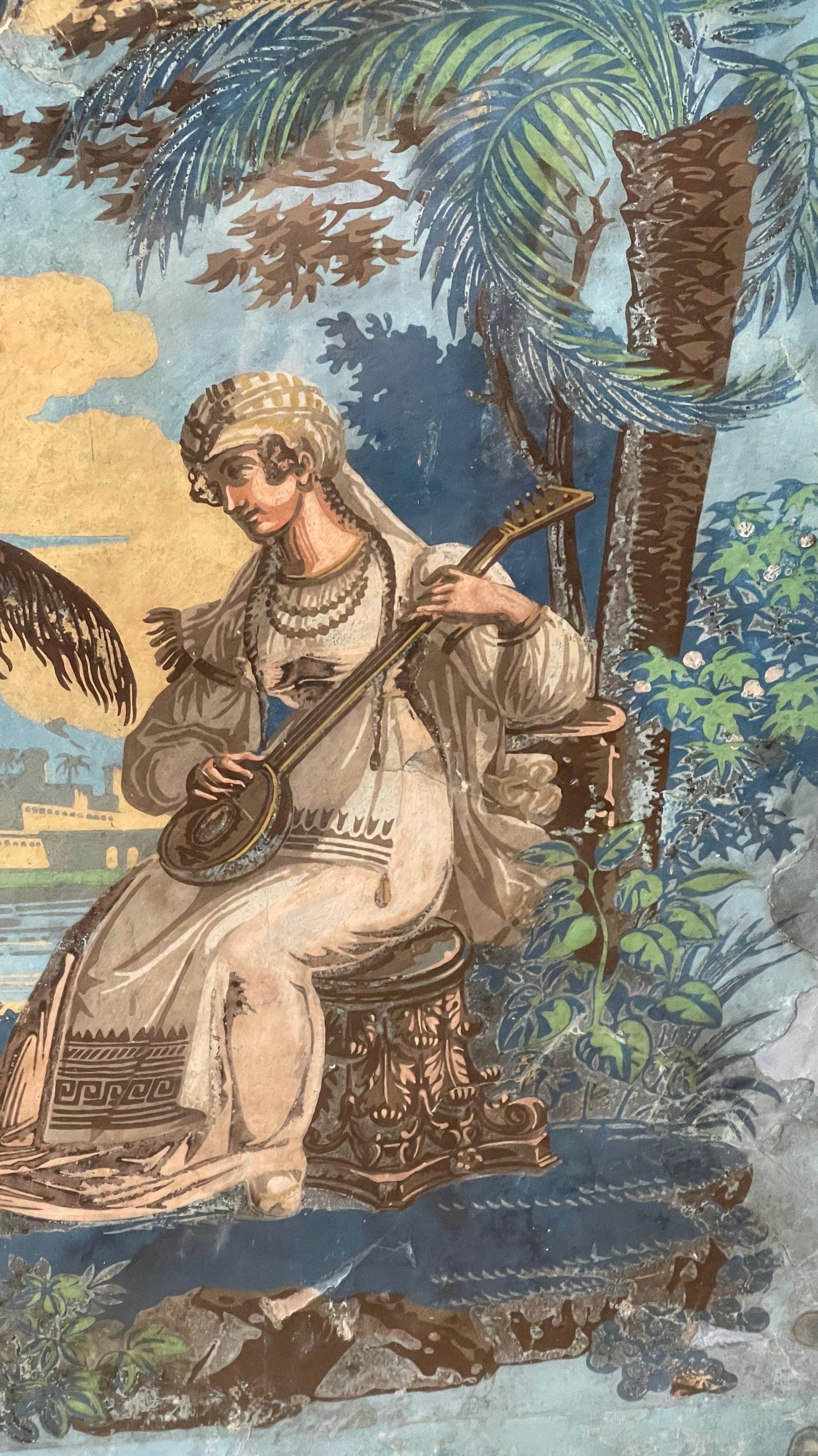 Papier peint français du XVIIIe siècle encadré, fond bleu de Prusse, une scène d'exotisme (grec ? turc ?) à cheval et une jeune fille jouant d'un instrument à cordes. Derrière le verre.
 